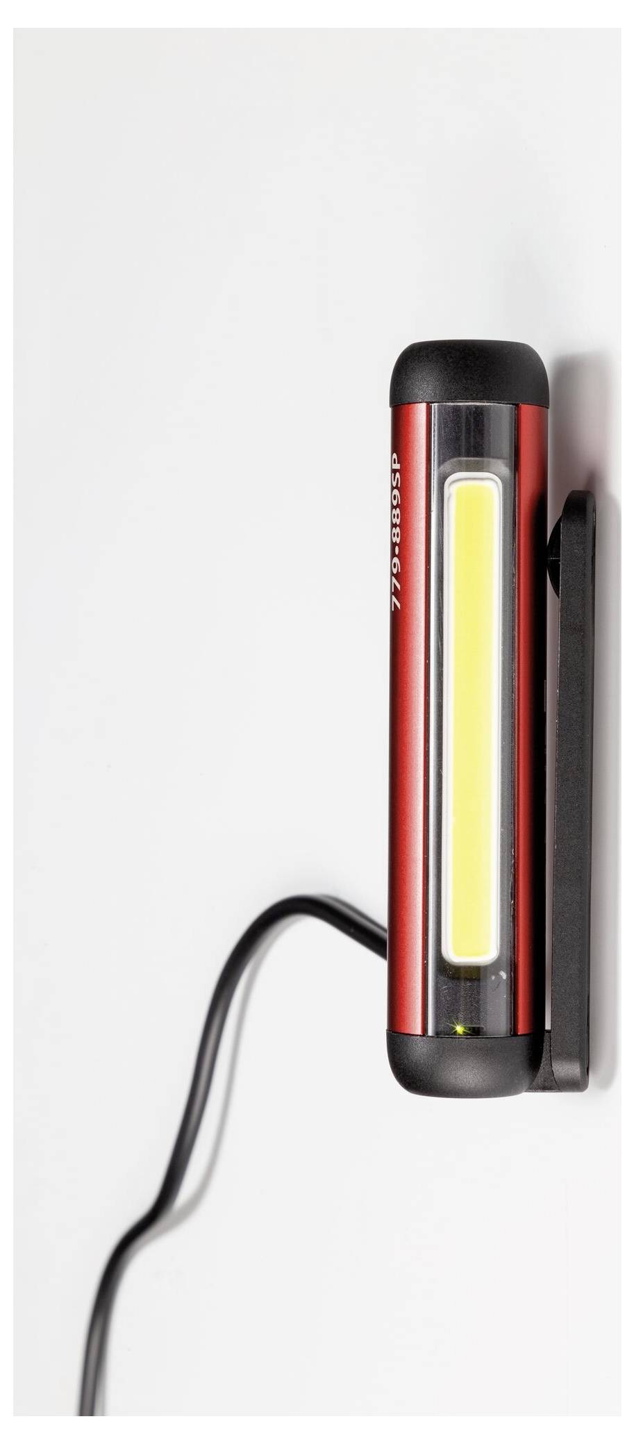 Červeno-černá LED pracovní lampa s připojeným napájecím kabelem, namontovaná na bílém povrchu.
