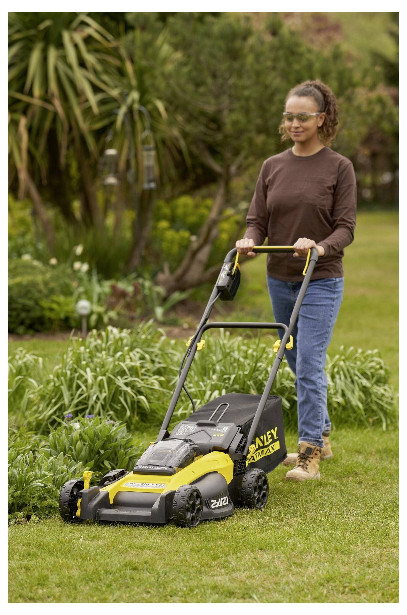 Rukavičky drží žlutou baterii „STANLEY FATMAX V20 Lithium-Ion 2.0Ah" určenou pro elektrické nářadí, kterou jsou právě zasouvány do bezdrátové vrtačky.