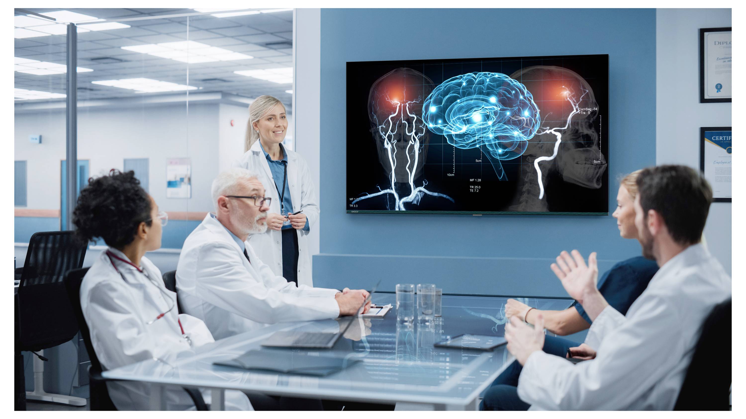Lékaři na schůzce sledují obrazovku se zářícím mozkem a dvěma siluetami profilů, diskutují o neurovědeckých poznatcích nebo zobrazování mozku pacienta.