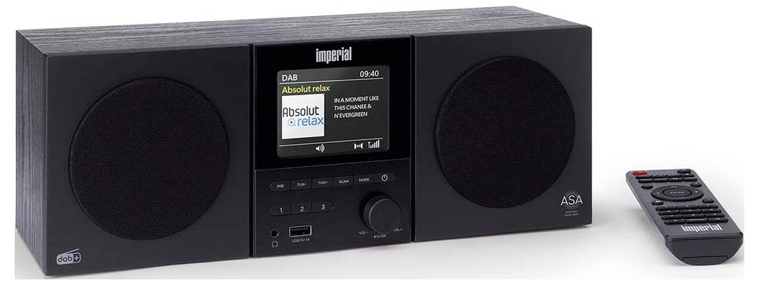 Černé stolní rádio se dvěma reproduktory, digitálním displejem a tlačítky pro ovládání. Vedle něj je umístěn dálkový ovladač.