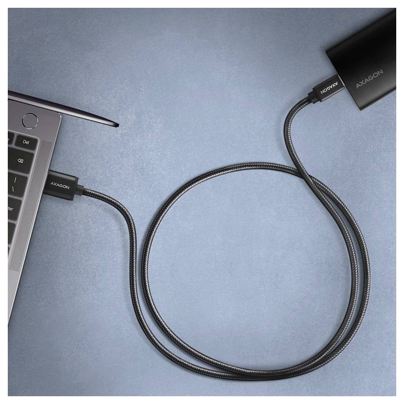 Kabel USB-C připojený k notebooku na levé straně, přičemž kabel je navinut přes modrý pozadí a vede k zařízení na pravé straně.