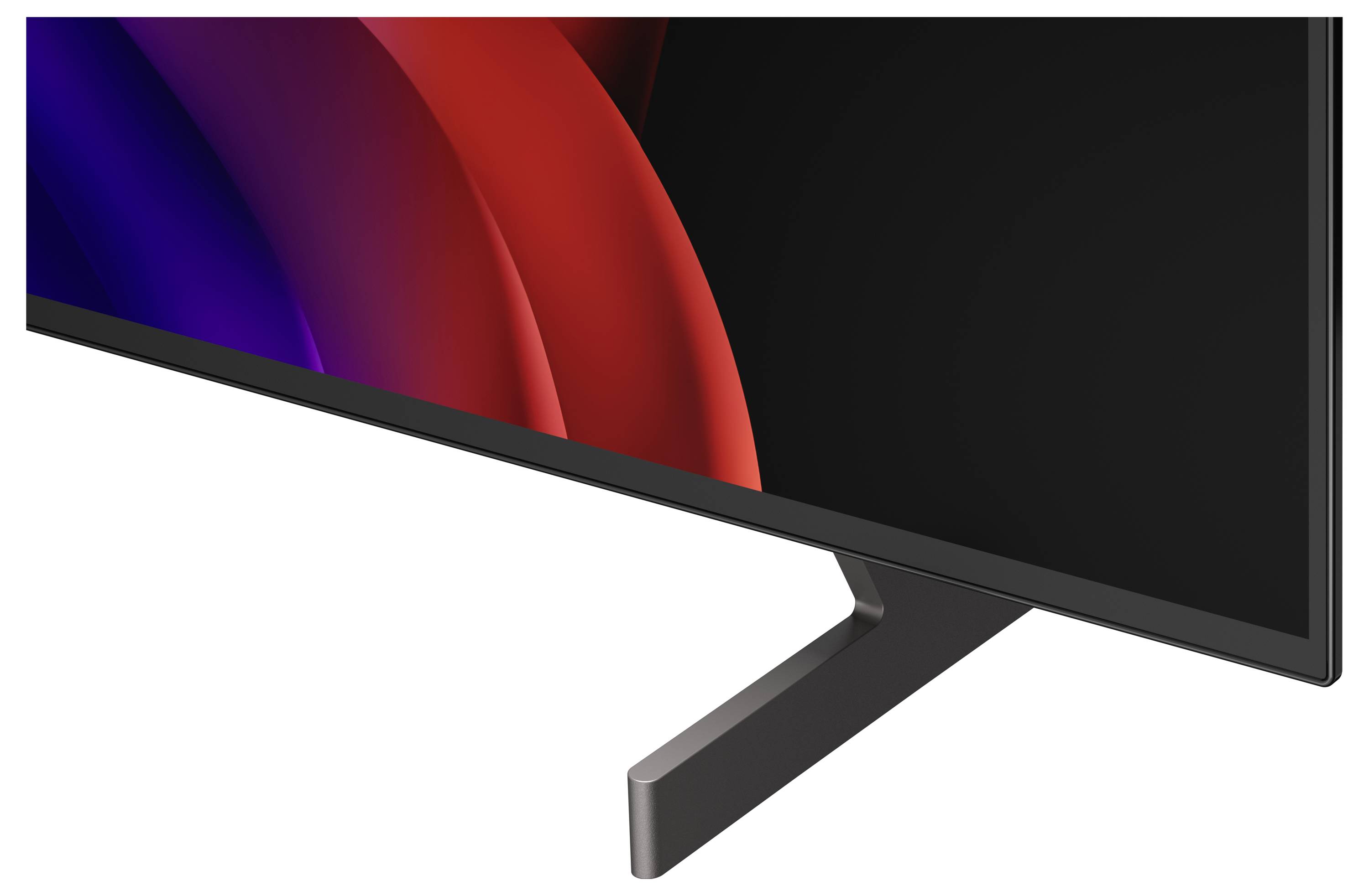 Detailní snímek monitoru s plochým displejem, černým rámem a podstavcem, na displeji je vidět tmavá abstraktní vlna v červené a modré barvě.