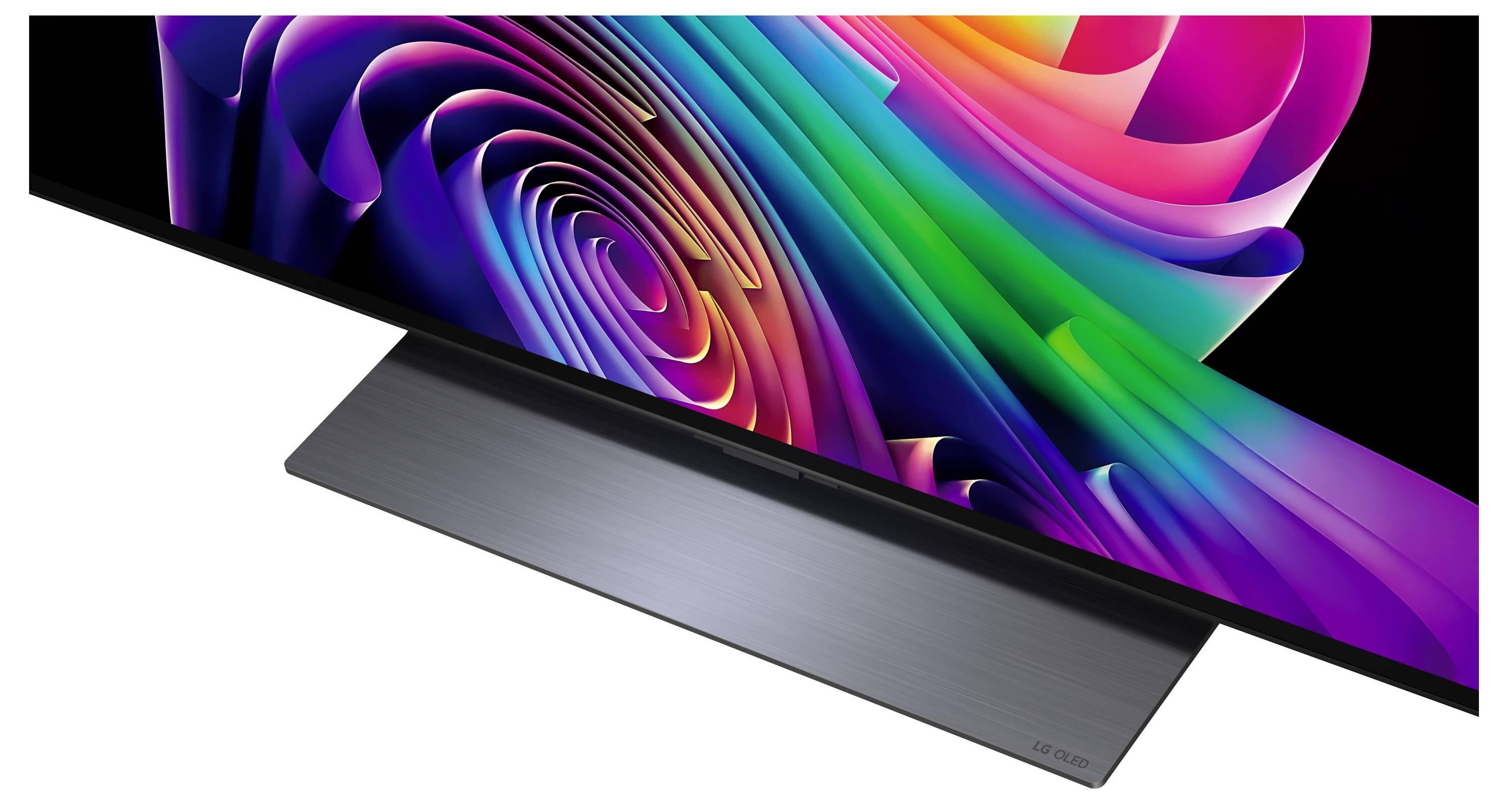Elegantní plochý monitor zobrazuje živou abstraktní víření duhy barev na černé obrazovce, zobrazeno na stojanu z kartáčovaného kovu.