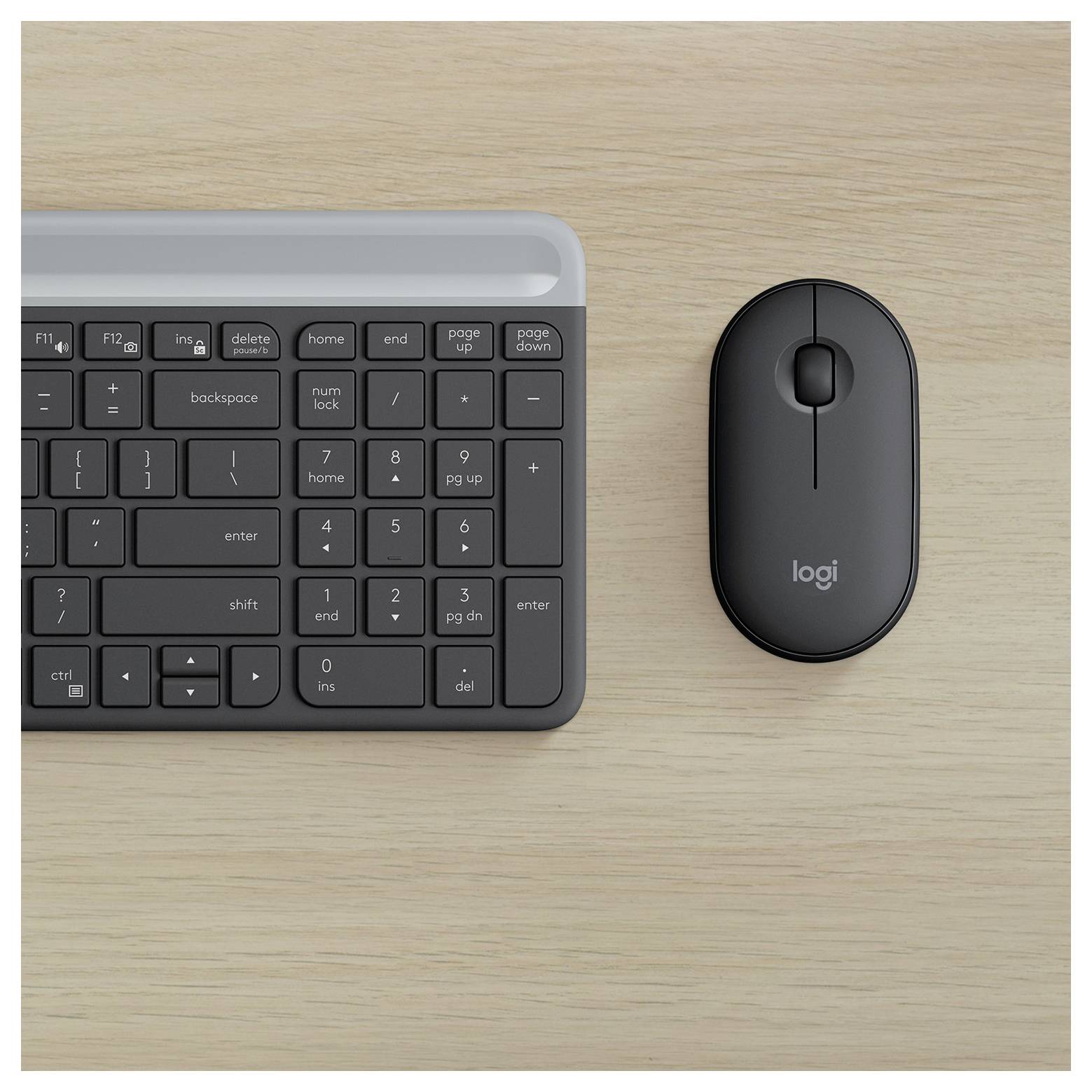 Pohled shora na bezdrátovou klávesnici a myš Logitech na světlém dřevěném stole.