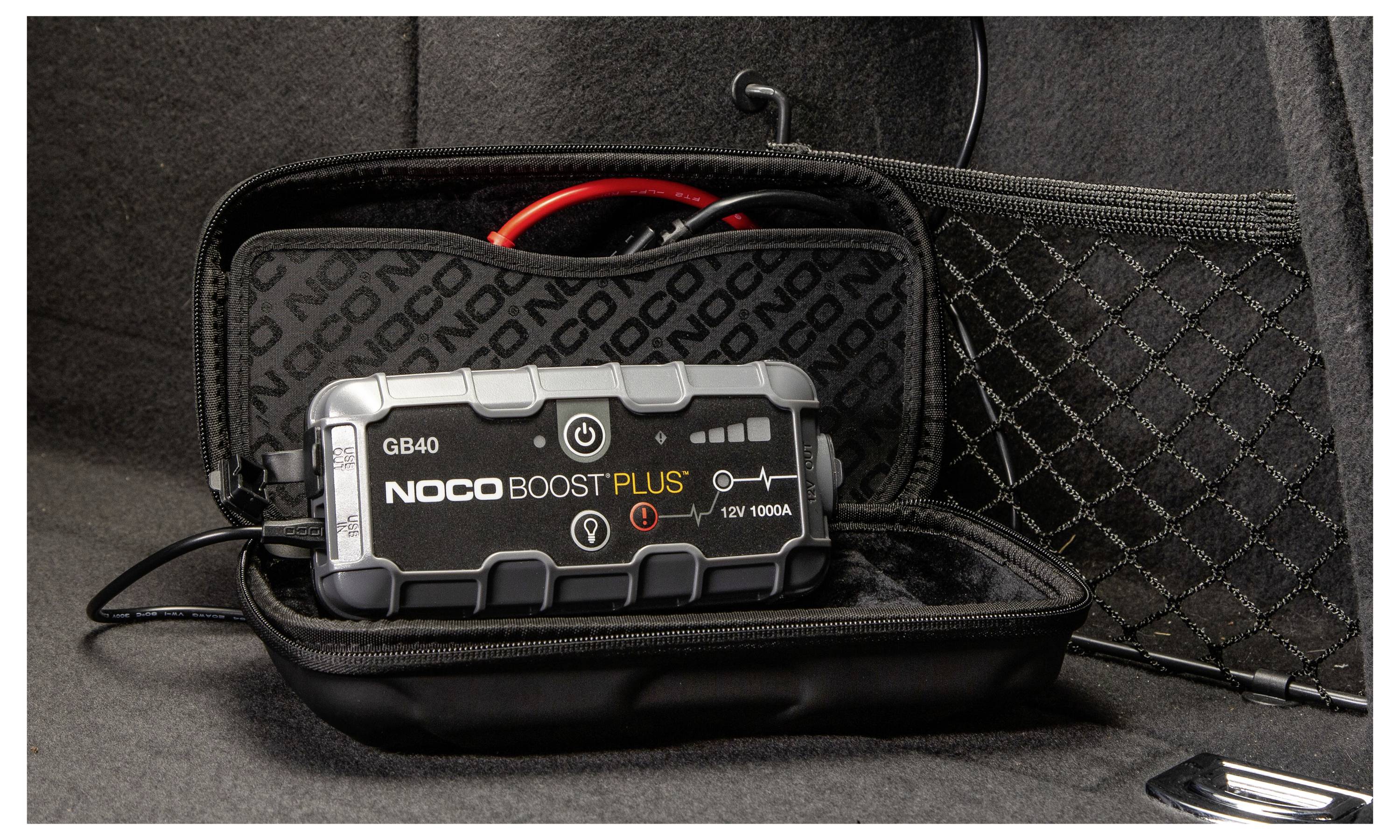 Startovací zařízení NOCO Boost Plus GB40 v černém pouzdře na zip s kabely a svorkami, zobrazené otevřené na tmavém povrchu.