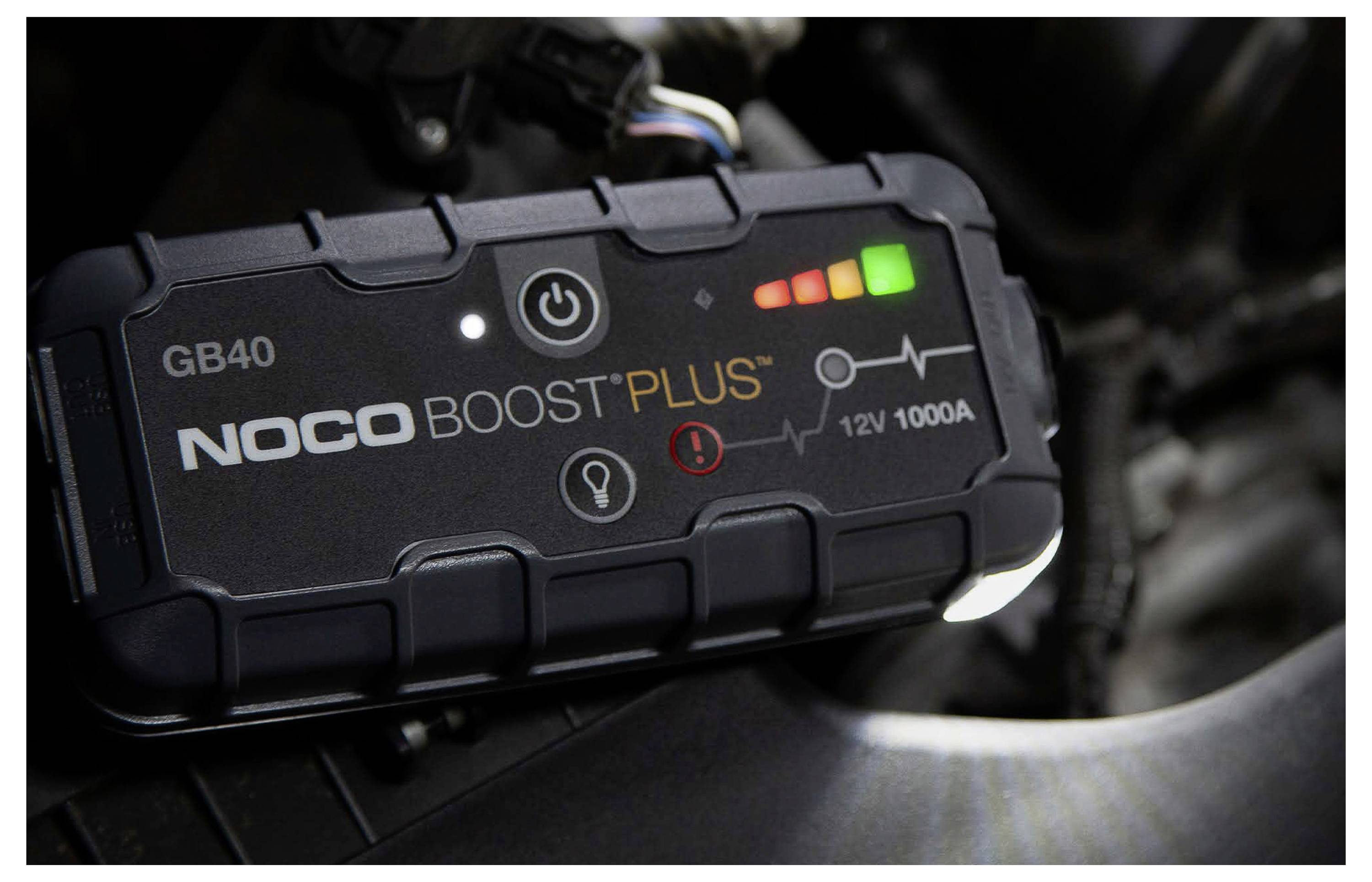 Přenosná startovací jednotka NOCO Boost Plus GB40 v autě, která zobrazuje tlačítko napájení, indikátory nabití a označení „12V 1000A".