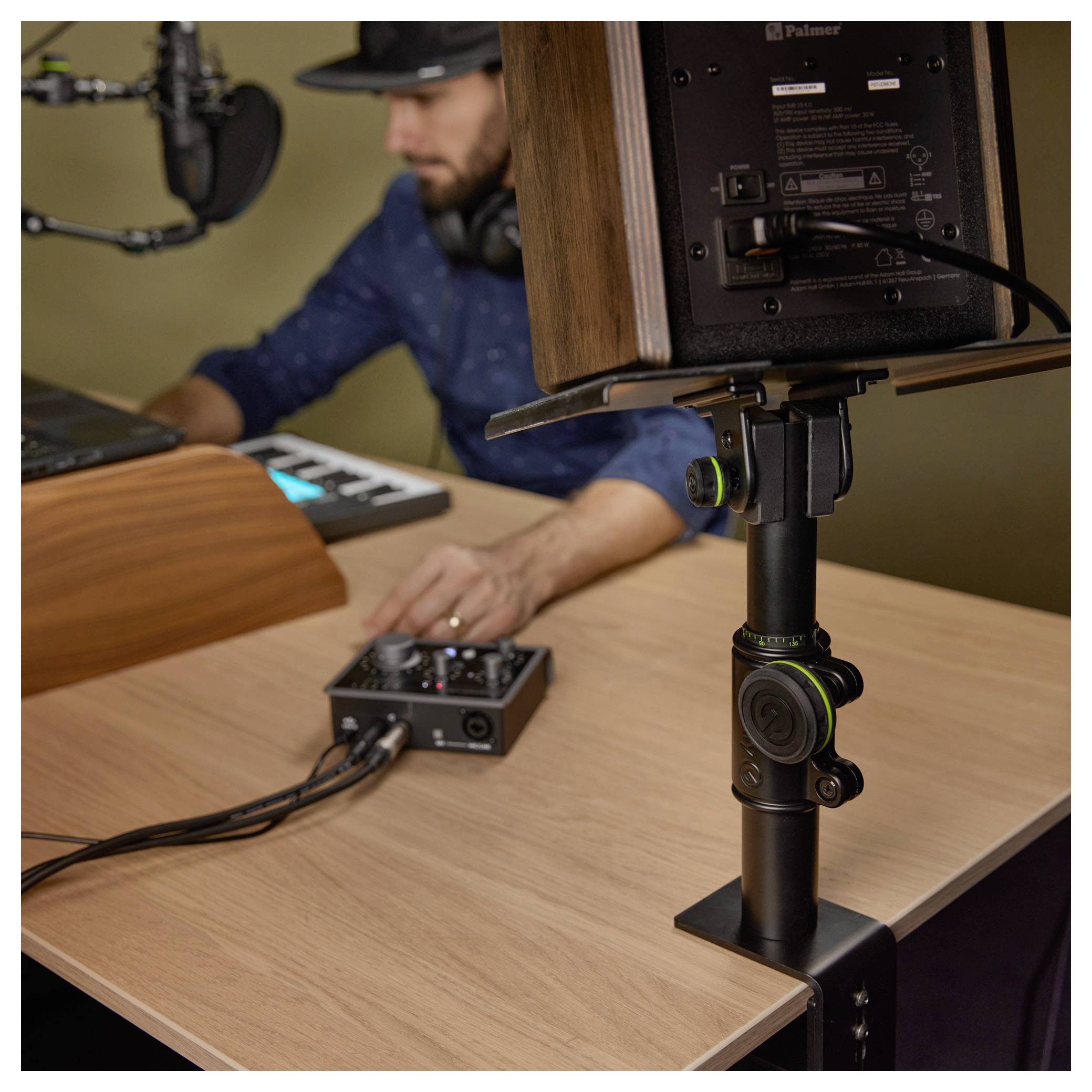 Nastavení podcastu s mikrofonem, monitorem kamery a zvukovým mixérem, kdy osoba upravuje vybavení u stolu