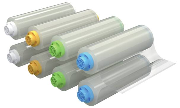 Naskládané válcové ink nebo tonerové kazety v šedé barvě s barevně rozlišenými víčky v žluté, zelené a modré barvě, uspořádané diagonálně na bílém pozadí.
