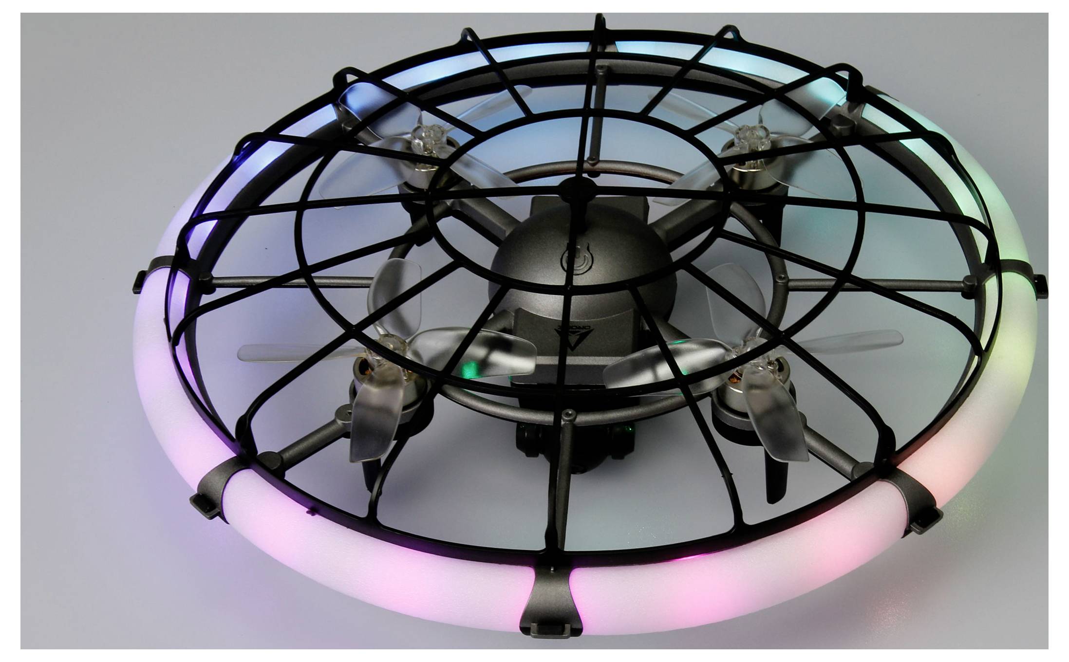 Malý černý létající dron v kulovém ochranném obalu se svítícími růžovými a zelenými LED světly kolem okraje.