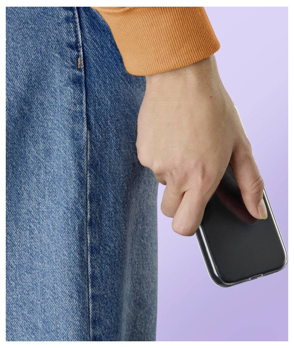 Detailní záběr na osobu držící smartphone u svého boku, oblečenou v oranžovém rukávu a modrých džínech před světle fialovým pozadím.