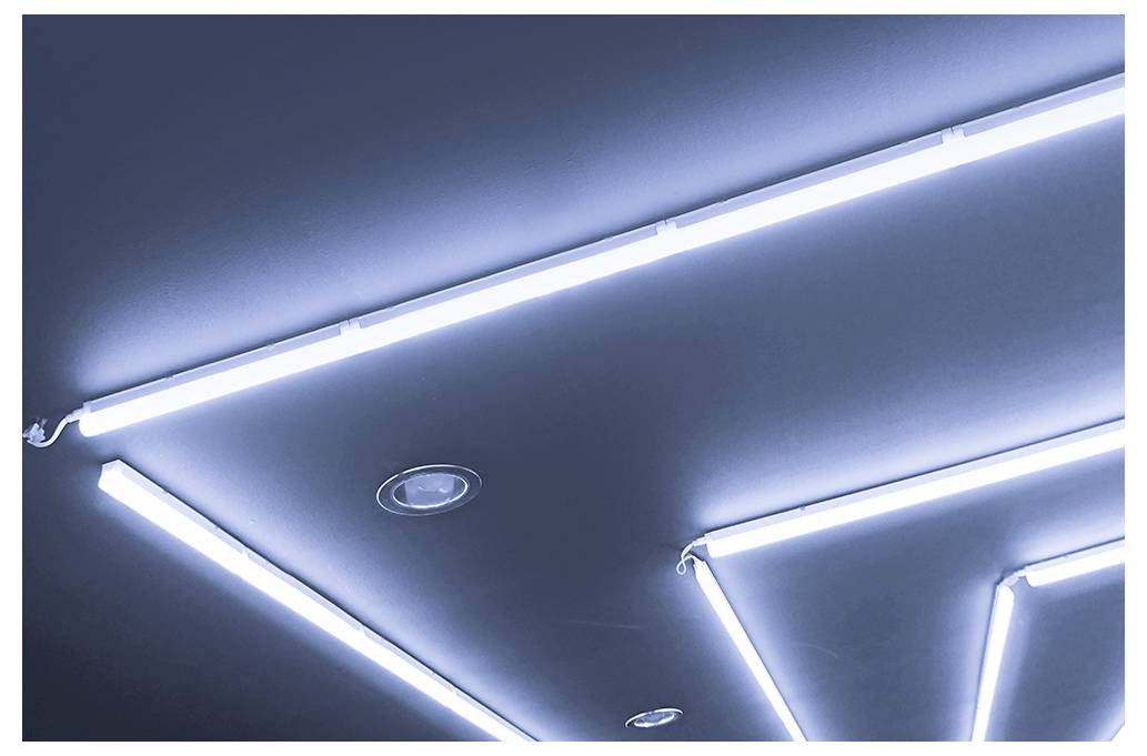 Strop s geometrickými LED pásky a vestavěnými reflektory, vytvářejícími moderní osvětlený vzor.