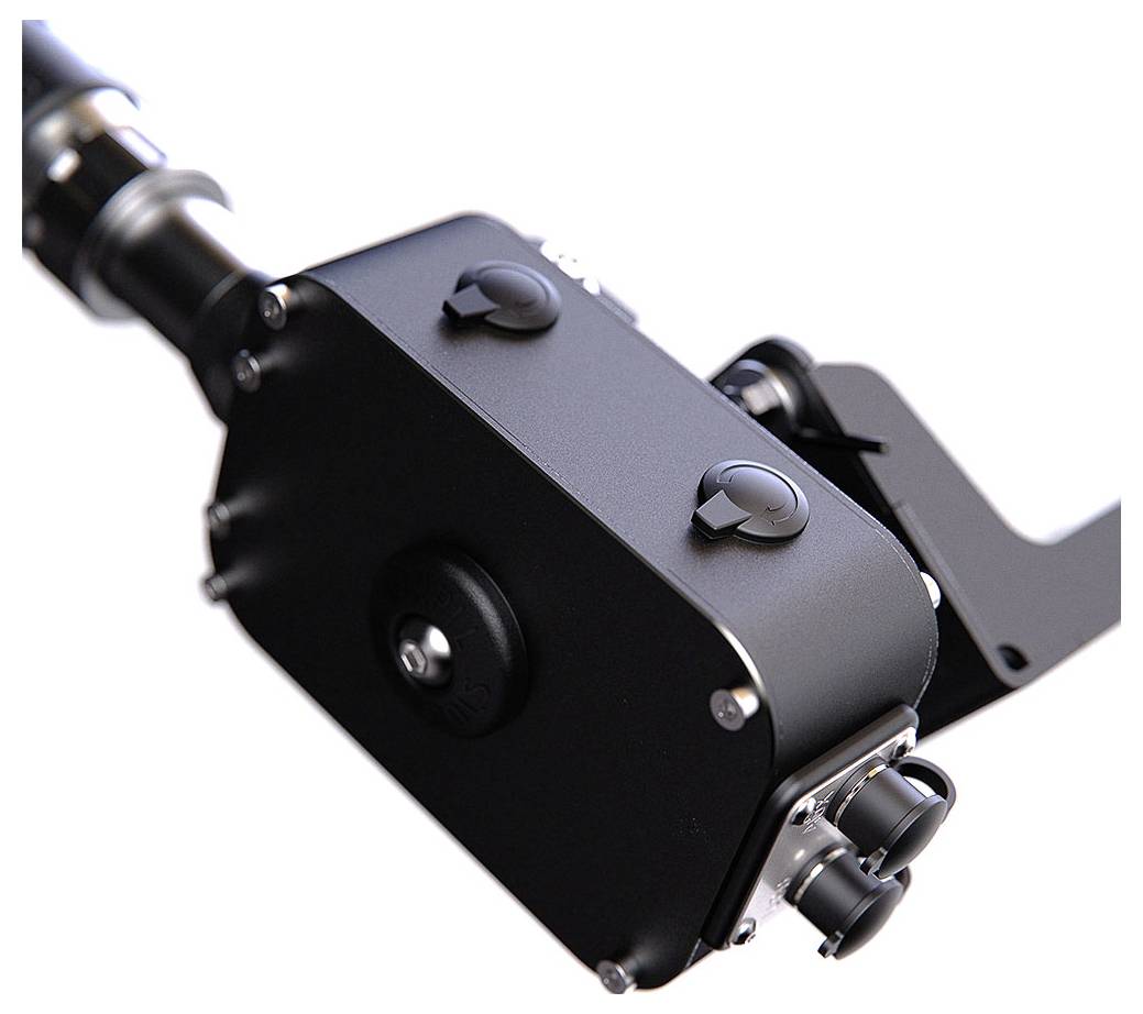 Detailní záběr černého kovového mechanického zařízení nebo fotoaparátu montu s šrouby, knoflíky a rukojetí na bílém pozadí.