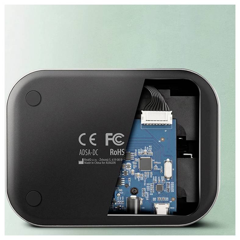 Přenosný počítač připojený na externí jednotku Axagon přes USB kabel na stole.