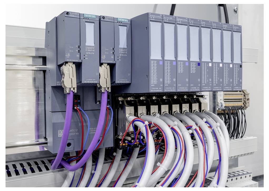 Průmyslová řídicí skříň se moduly Siemens SIMATIC PLC a mnoha připojenými kabely a svorkovnicemi.