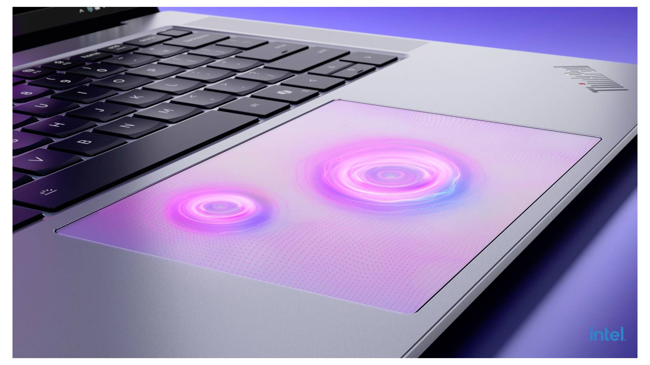 Detailní snímek klávesnice a touchpadu notebooku s touchpadem zářícím v růžové a fialové barvě, který ukazuje dotyková nebo gesterická interakci.