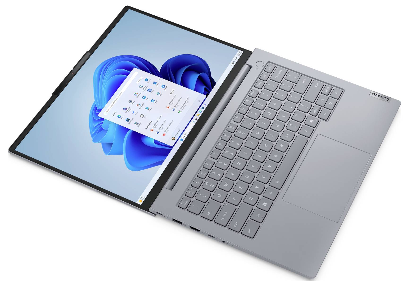 Šedý notebook zobrazený otevřený pod úhlem, na kterém je vidět plocha systému Windows 11 a nabídka Start na dotykové obrazovce