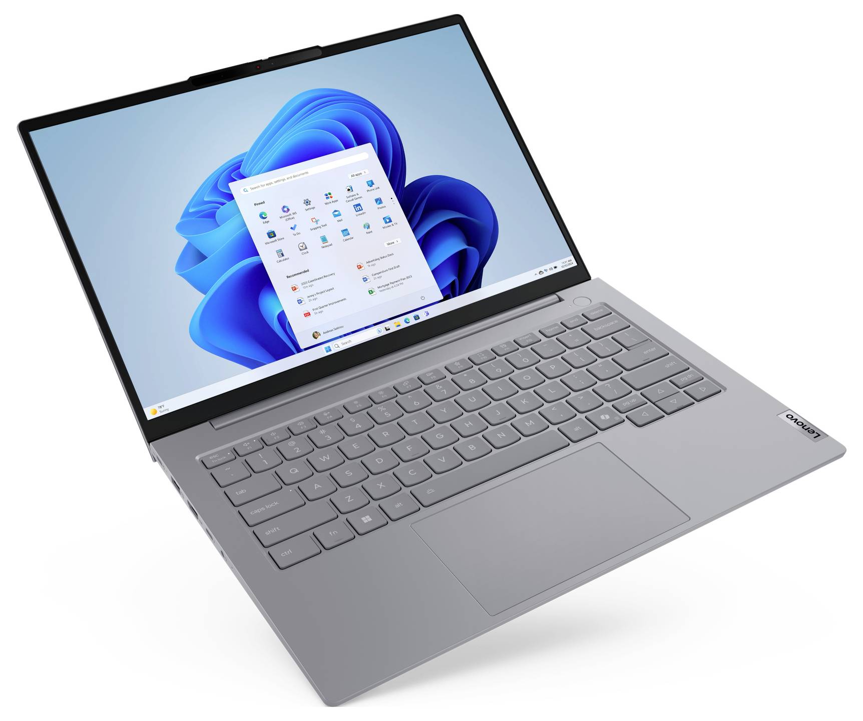 Stříbrný laptop zobrazující plochu systému Windows 11 s otevřenou nabídkou Start na bílém pozadí.