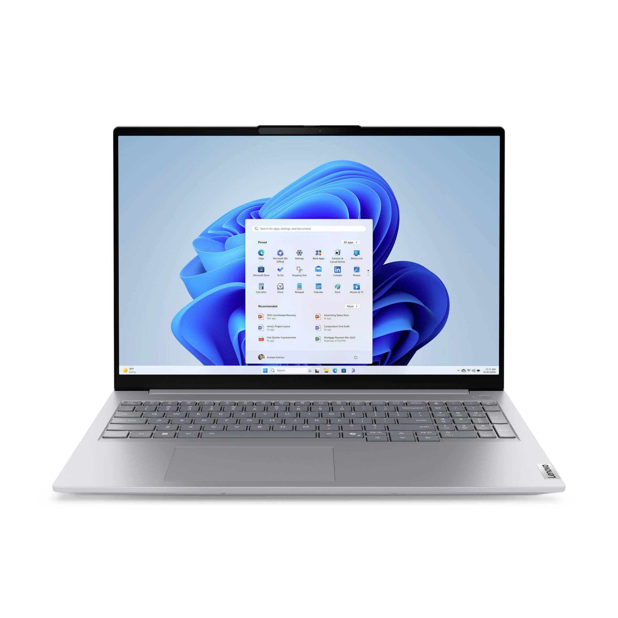 Stříbrný laptop zobrazující plochu systému Windows 11 s otevřenou nabídkou Start na modrém abstraktním pozadí.
