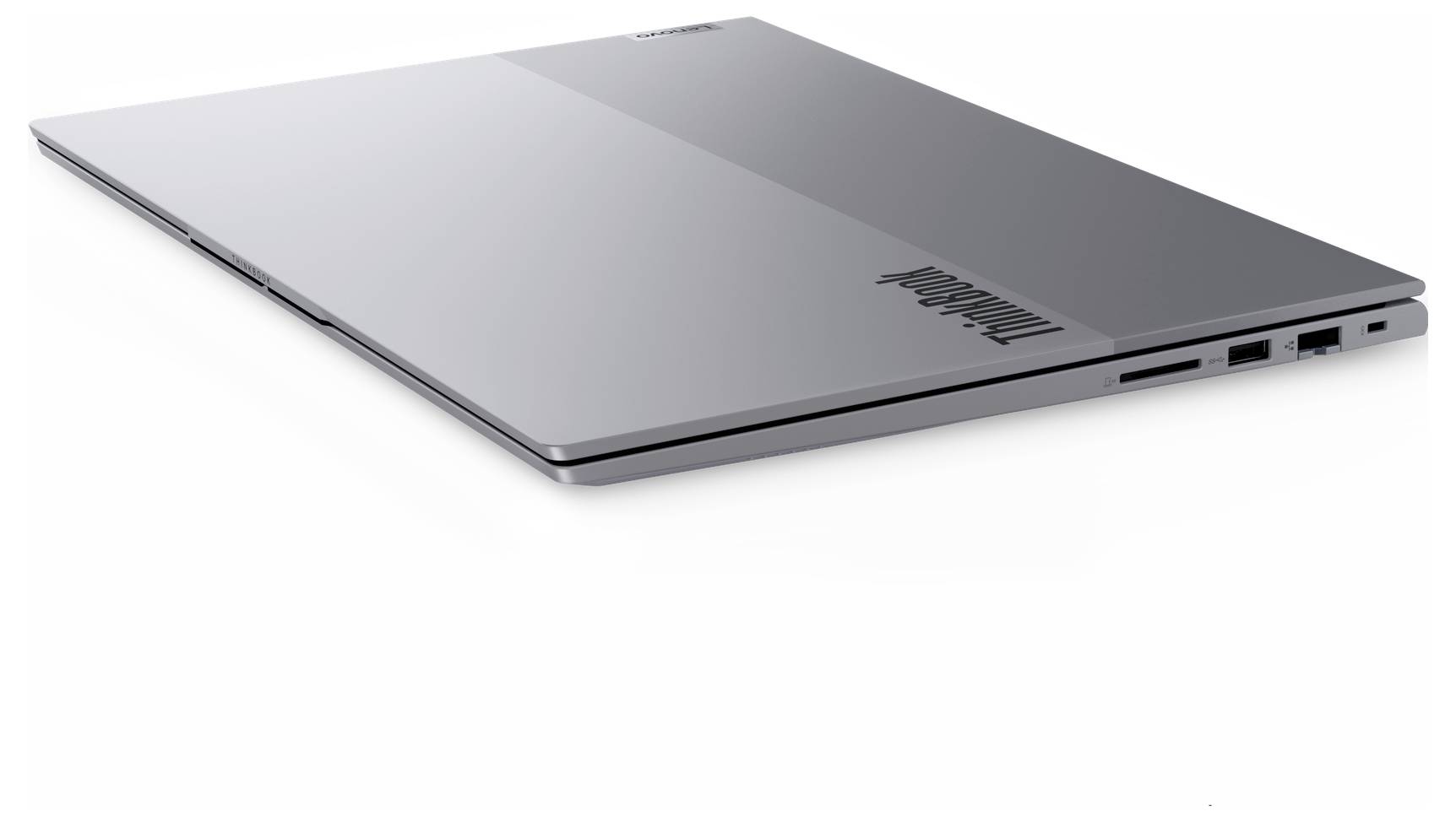Zavřený stříbrný laptop Lenovo zobrazený z úhlového horního pohledu na bílém pozadí.