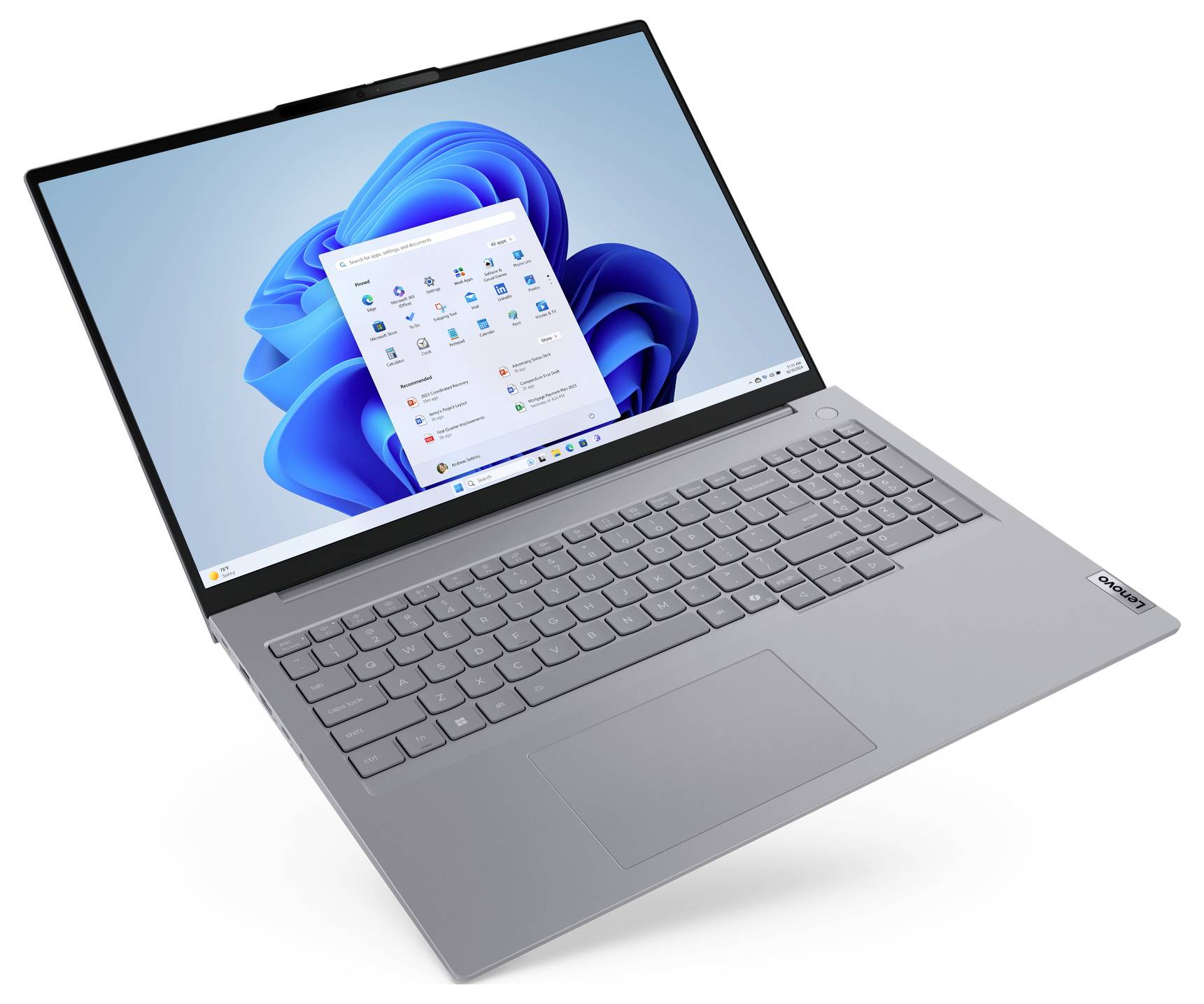 Stříbrný notebook Lenovo otevřený na bílém pozadí, zobrazující plochu Windows 11 a nabídku Start.