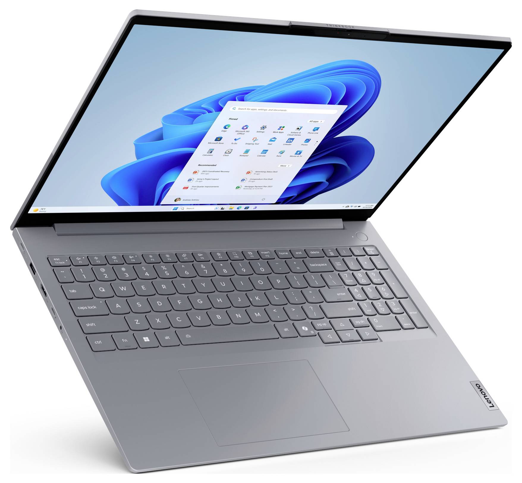 Šedý notebook Lenovo otevřený v úhlu, zobrazující plochu Windows 11 a centralizovanou nabídku Start na obrazovce.