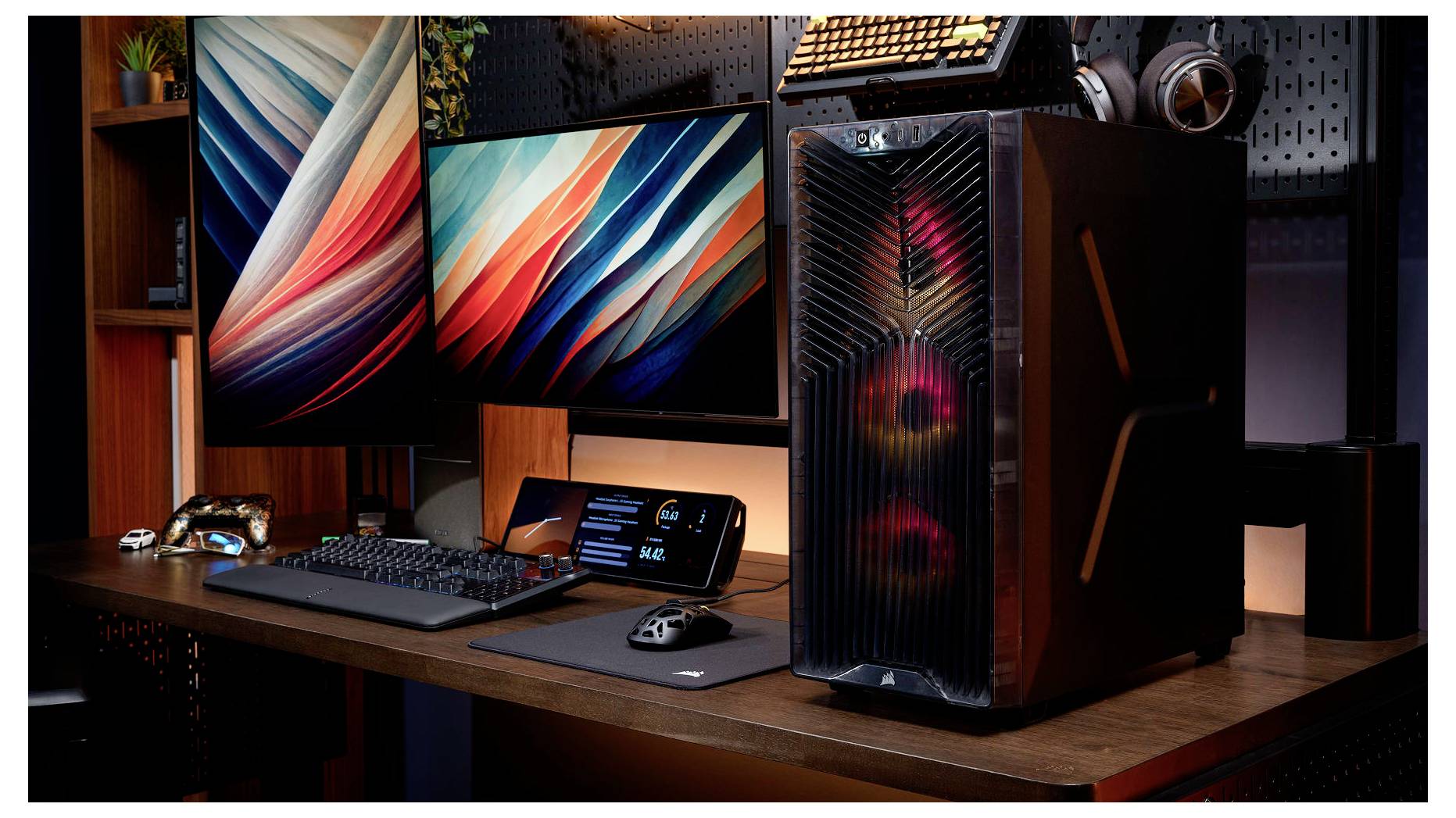 Vysokokapacitní herní setup s dvěma monitory, RGB osvětleným PC věží, klávesnicí, myší a sluchátky na dřevěném stole.