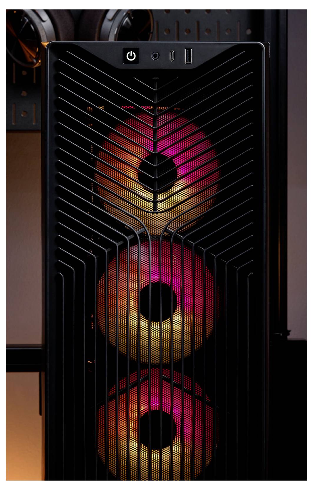 Přední pohled na černou věž PC skříně se třemi zářícími RGB ventilátory viditelná za diagonálně rozřazenou mřížkou.