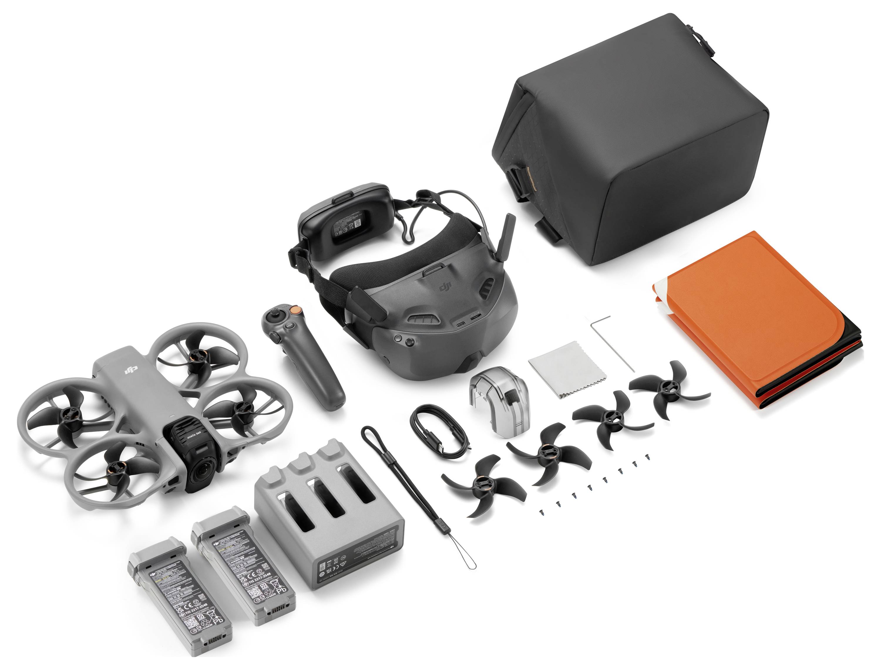 FPV dronový set s komponenty rozloženými na bílém pozadí, včetně malého kvadrokoptéry, brýlí, ovladače, baterií, nabíječky, antén, vrtulí, nástrojů a přepravních pouzder.