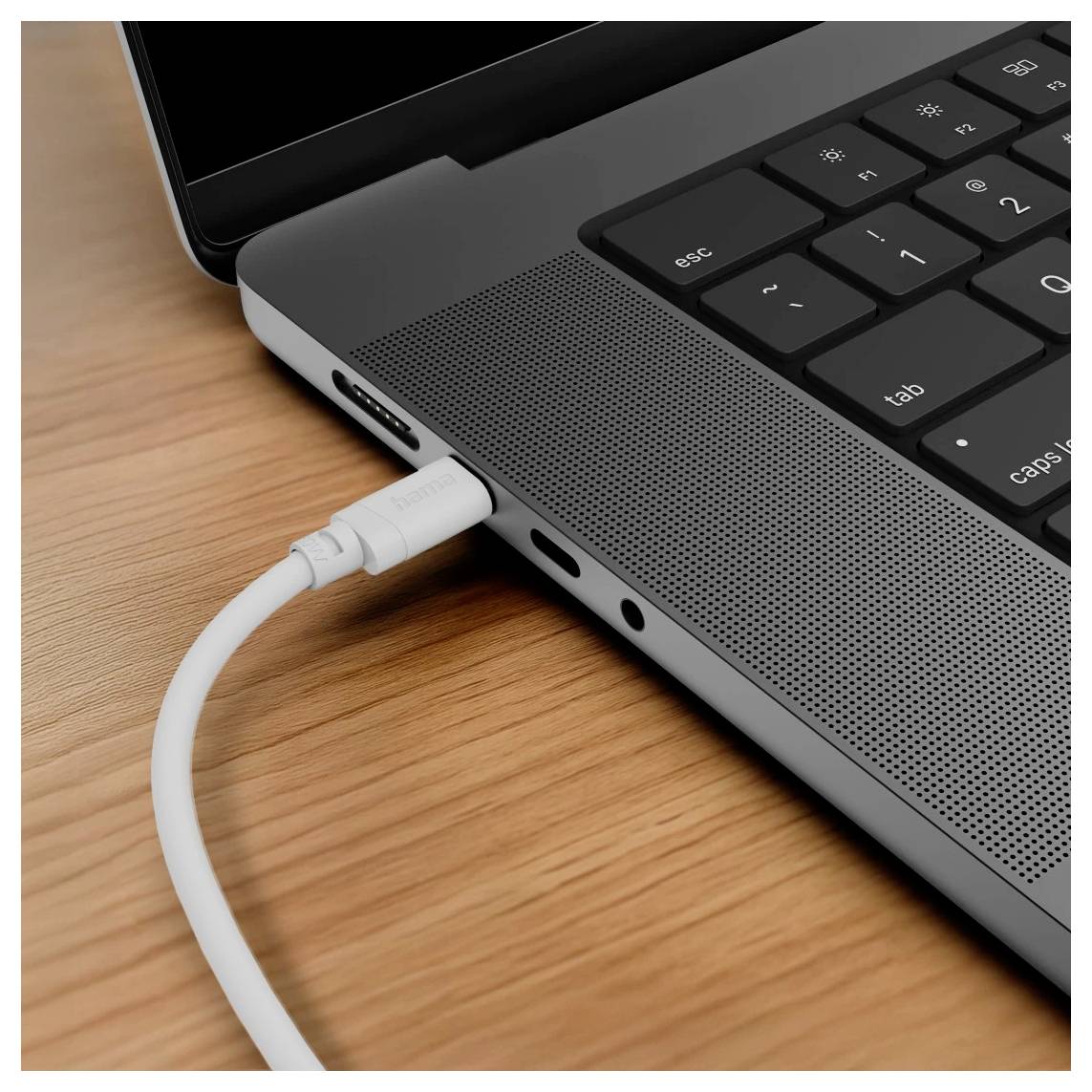 Bílý kabel USB-C zapojený do strany notebooku na dřevěném stole.