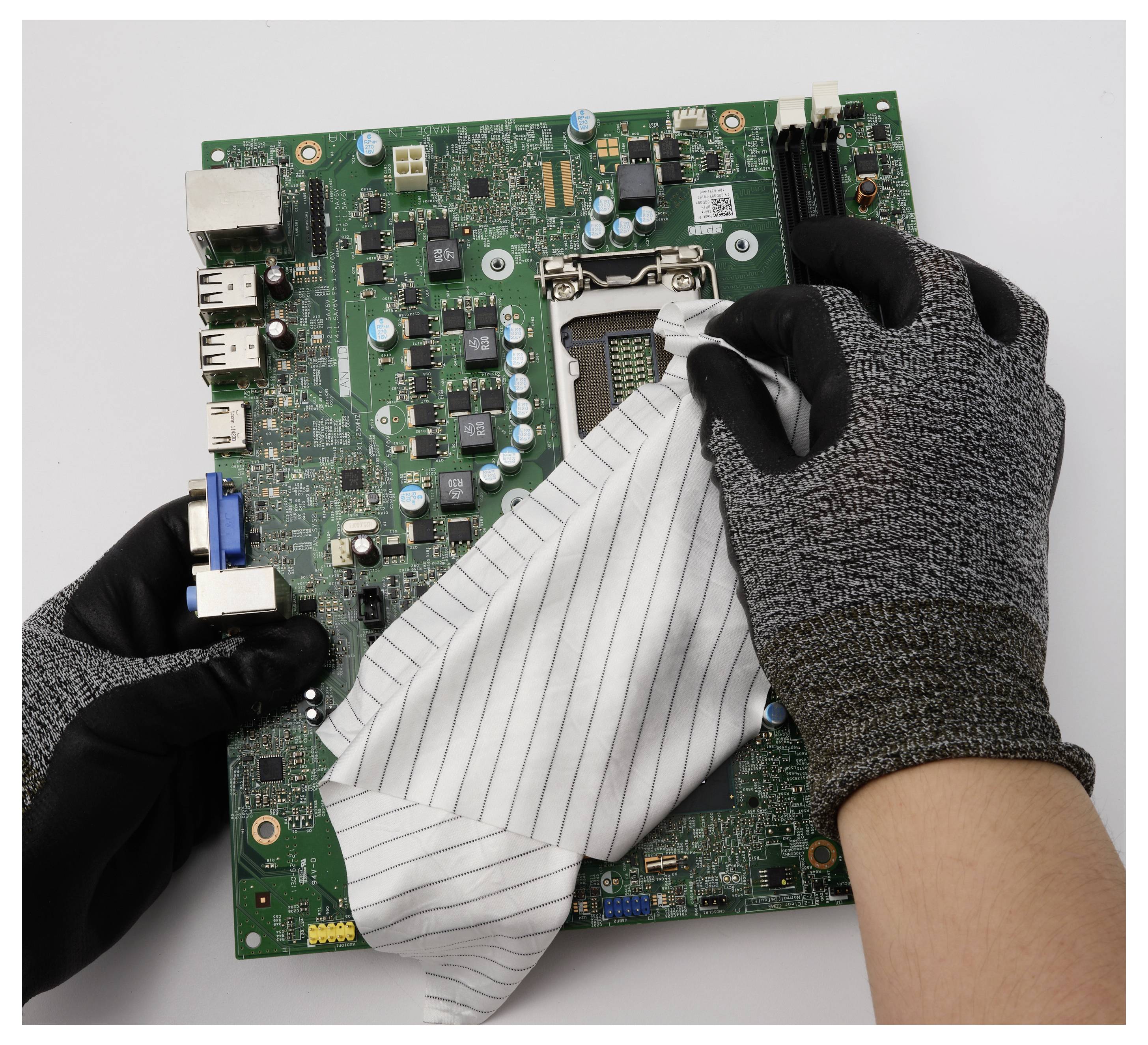 Rukavované ruce čistící prach z počítačové desky hadříkem.