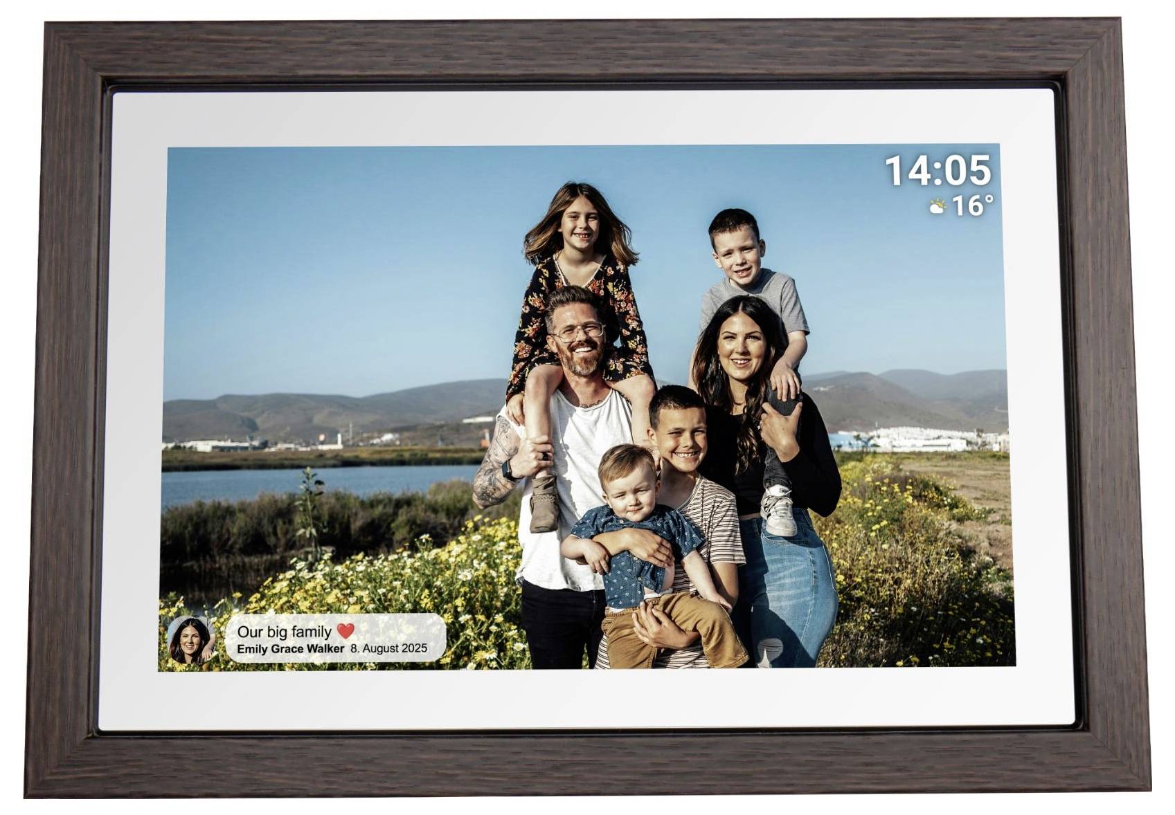 Digitální fotorám zobrazující rodinný portrét v přírodě u vody a hor s digitálními hodinami a informací o počasí ukazující 14:05 a 16°.