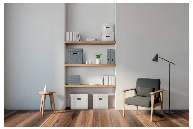 Minimalistický moderní obývací pokoj s šedým křeslem, stojací lampou, policemi, úložnými krabicemi a malou dřevěnou stoličkou na dřevěné podlaze.