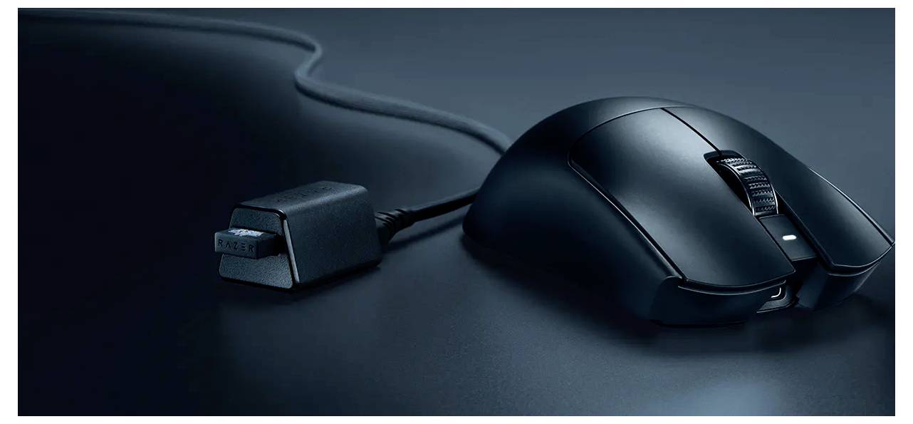 Černá drátová počítačová myš s USB konektorem na tmavém povrchu, zobrazena v detailním záběru.