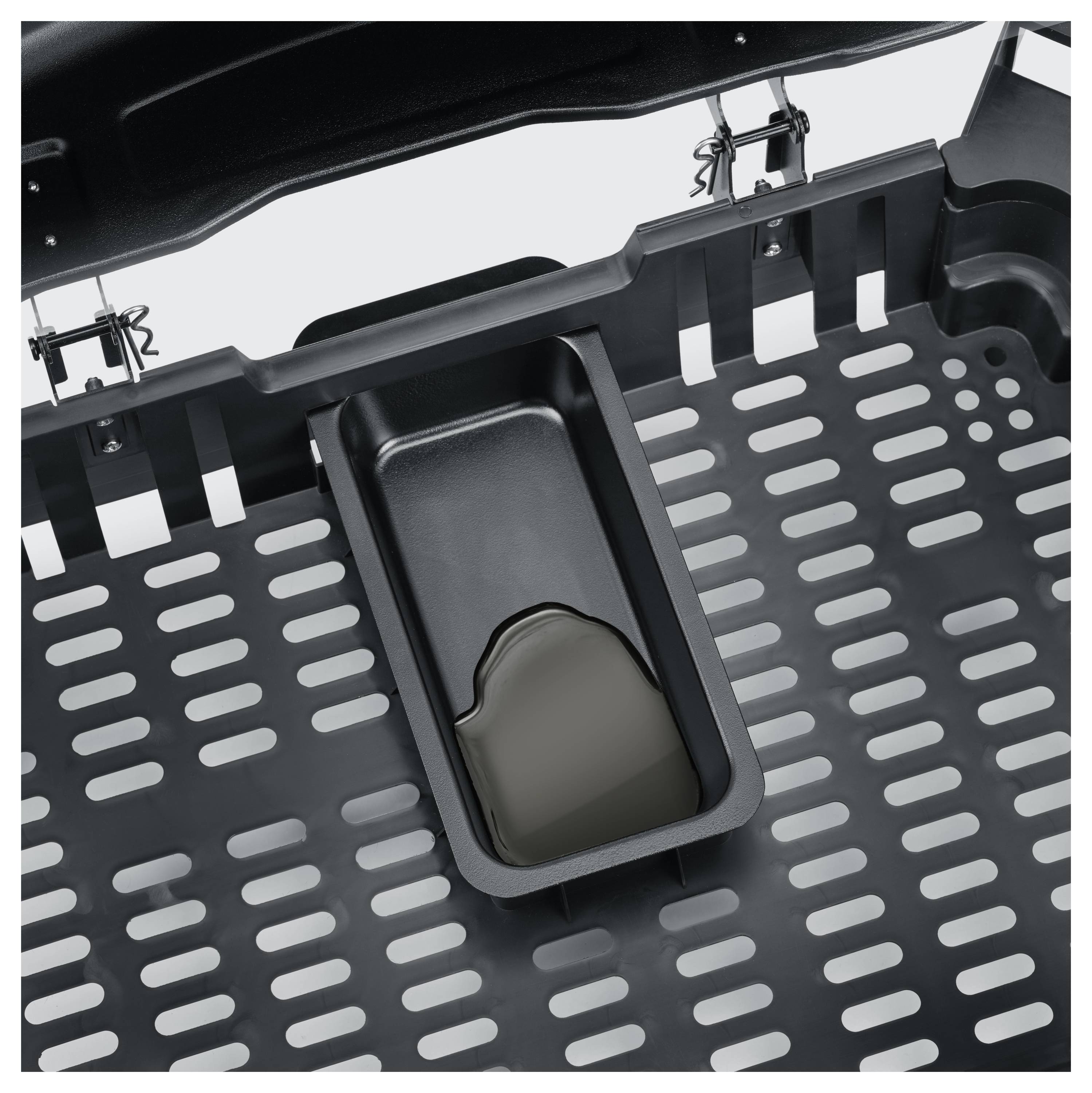 Detailní snímek černého kovového grilu nebo podnosu s perforovanými štěrbinami a centrální obdélníkovou odkapávací mističkou obsahující kapalinu.