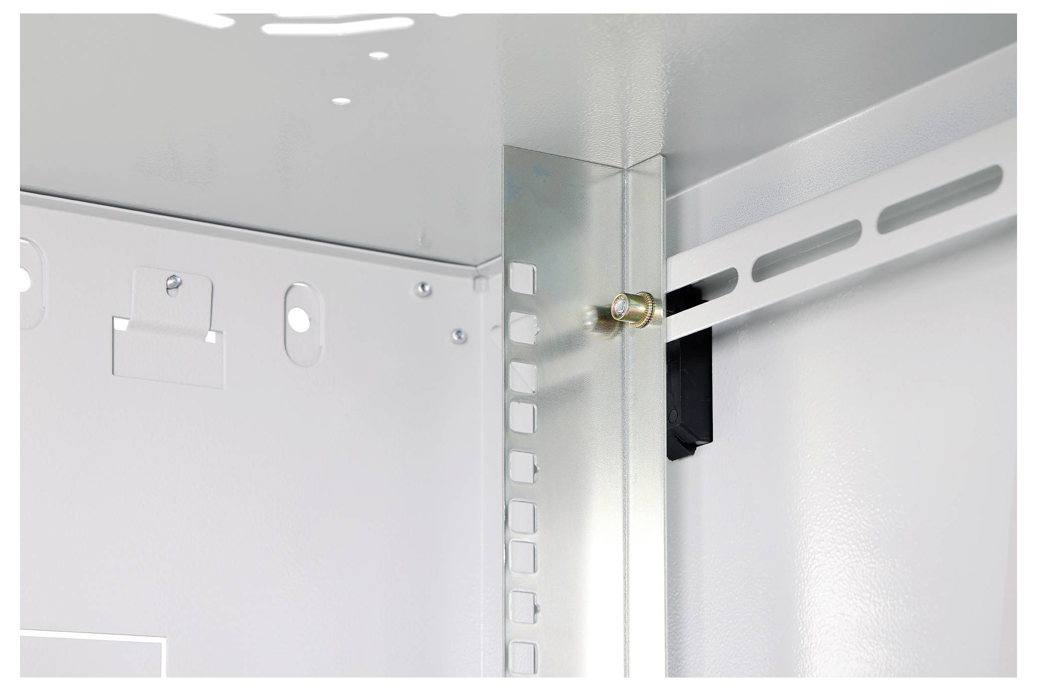 Detailní pohled na vnitřní roh kovové skříně s panty a montážními konzolami na bílých panelech.