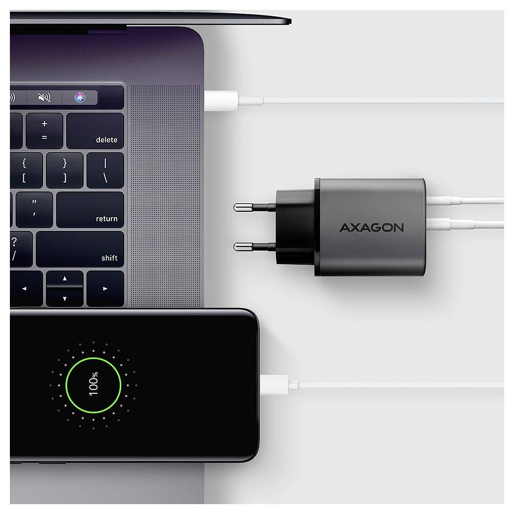 Pohled shora na notebook nabíjející se přes nástěnný adaptér AXAGON USB-C a připojenou powerbou, s kabely zapojenými do obou zařízení.