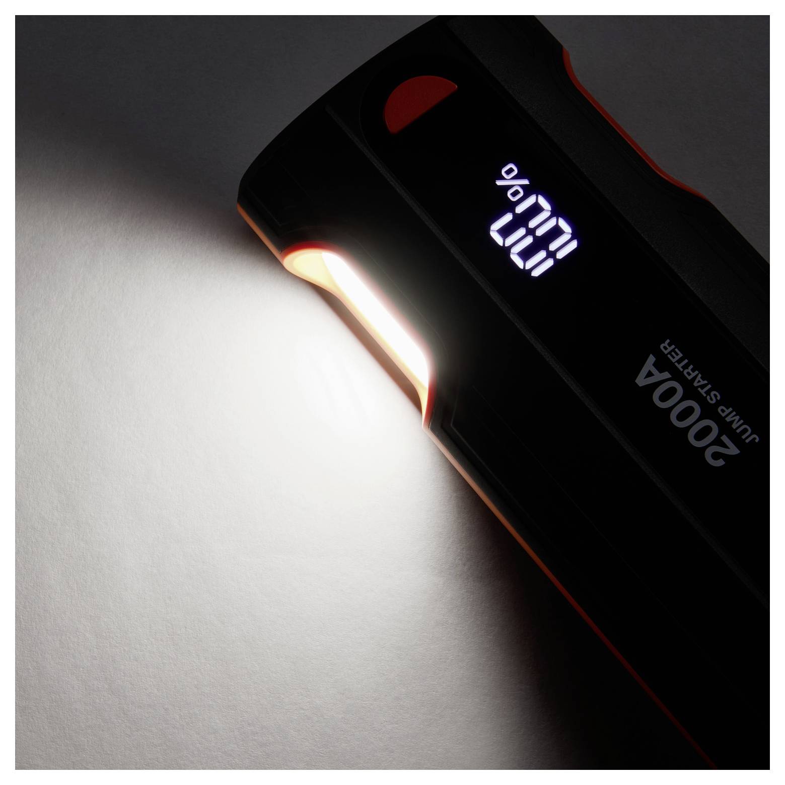 Přenosná černá USB LED svítilna označená „startovací zařízení 2000A" svítící jasným paprskem na povrch s digitálním displejem baterie.