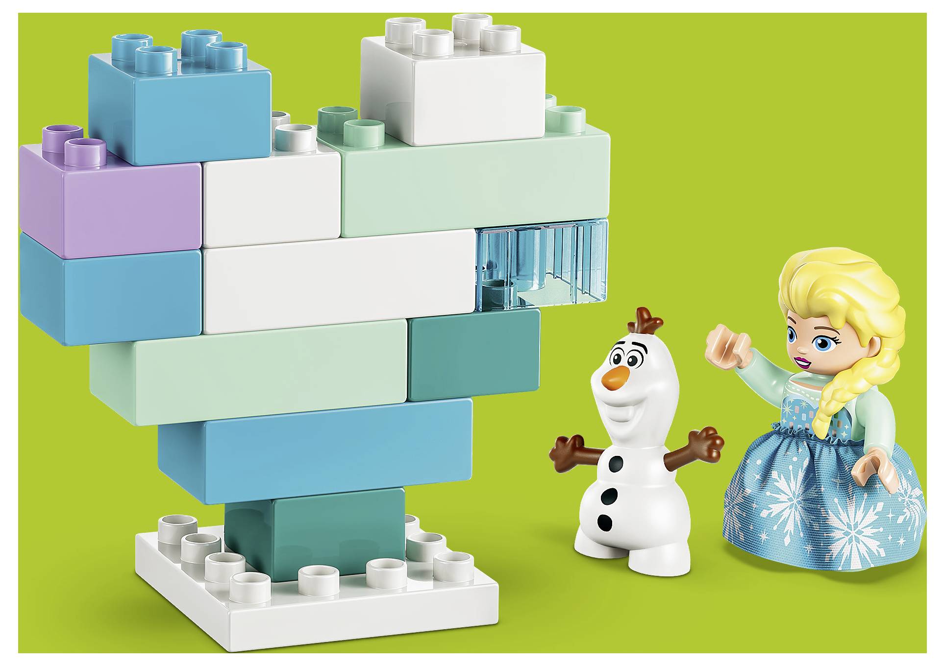 Hračka ve stylu LEGO model tyrkysového a bílého srdce na podstavci s postavičkami Olafa a Elsy vedle na zeleném pozadí.