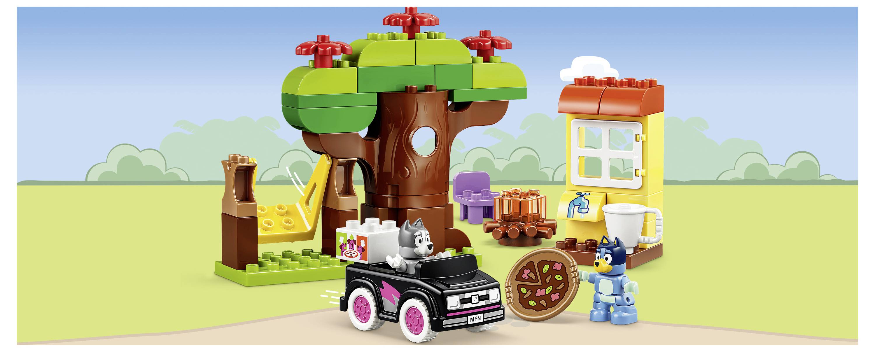 LEGO stylizovaná scéna tržiště v domku na stromě s černým autem, šedou kočkou, modrou minifigurkou a vozíkem s ovocem pod velkým stromem.