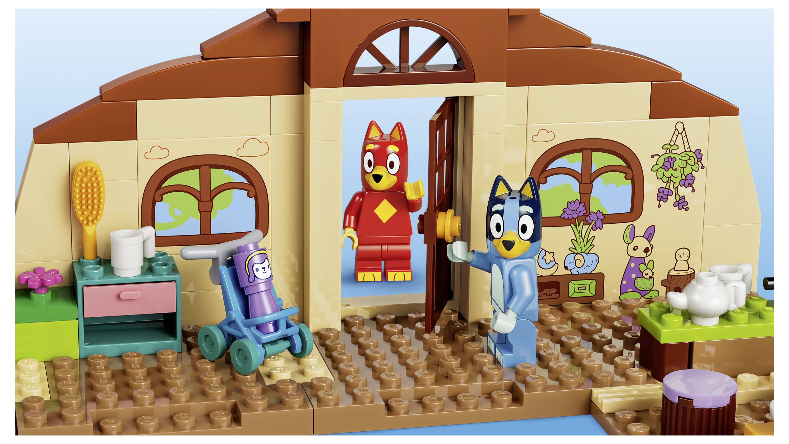 LEGO Blueyův hrací domek se Bluey ve dveřích, Bingo uvnitř a s hračkou vysavačem, stolem a čajníkem v dekorovaném pokoji.