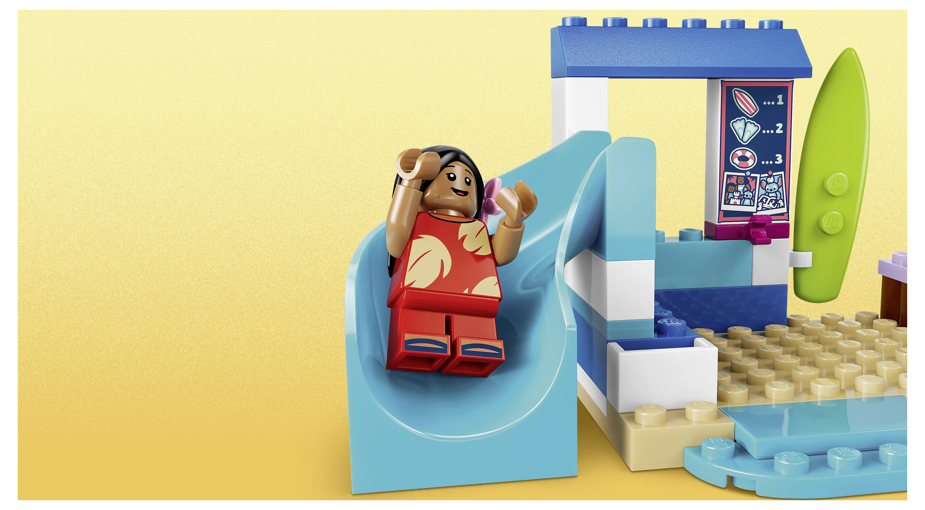 Minifigurka LEGO se vozí na tyrkysové skluzavce vedle bazénu a surfboardu v malé soupravě s plážovou tématikou.