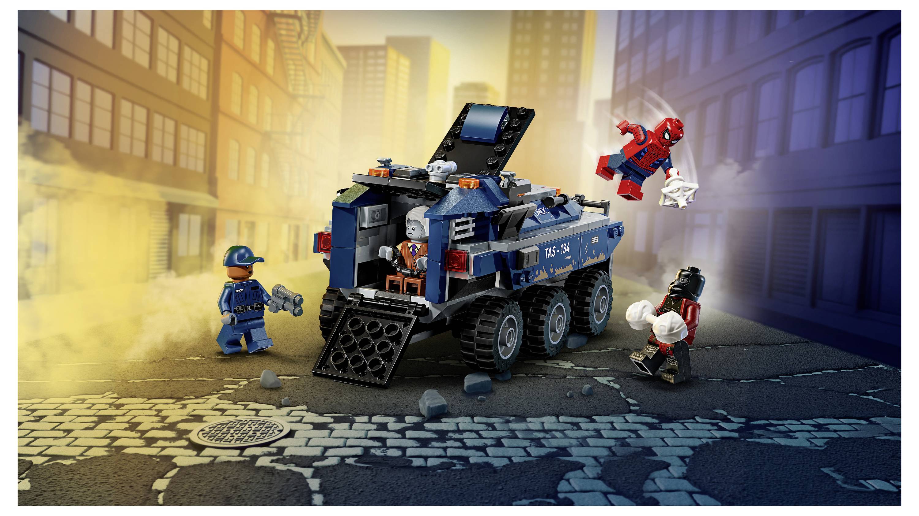 LEGO policejní obrněný vůz na městské ulici pronásleduje Spider-Mana, vedle něj jsou policista a maskovaný padouch obklopeni kouřem a troskami.