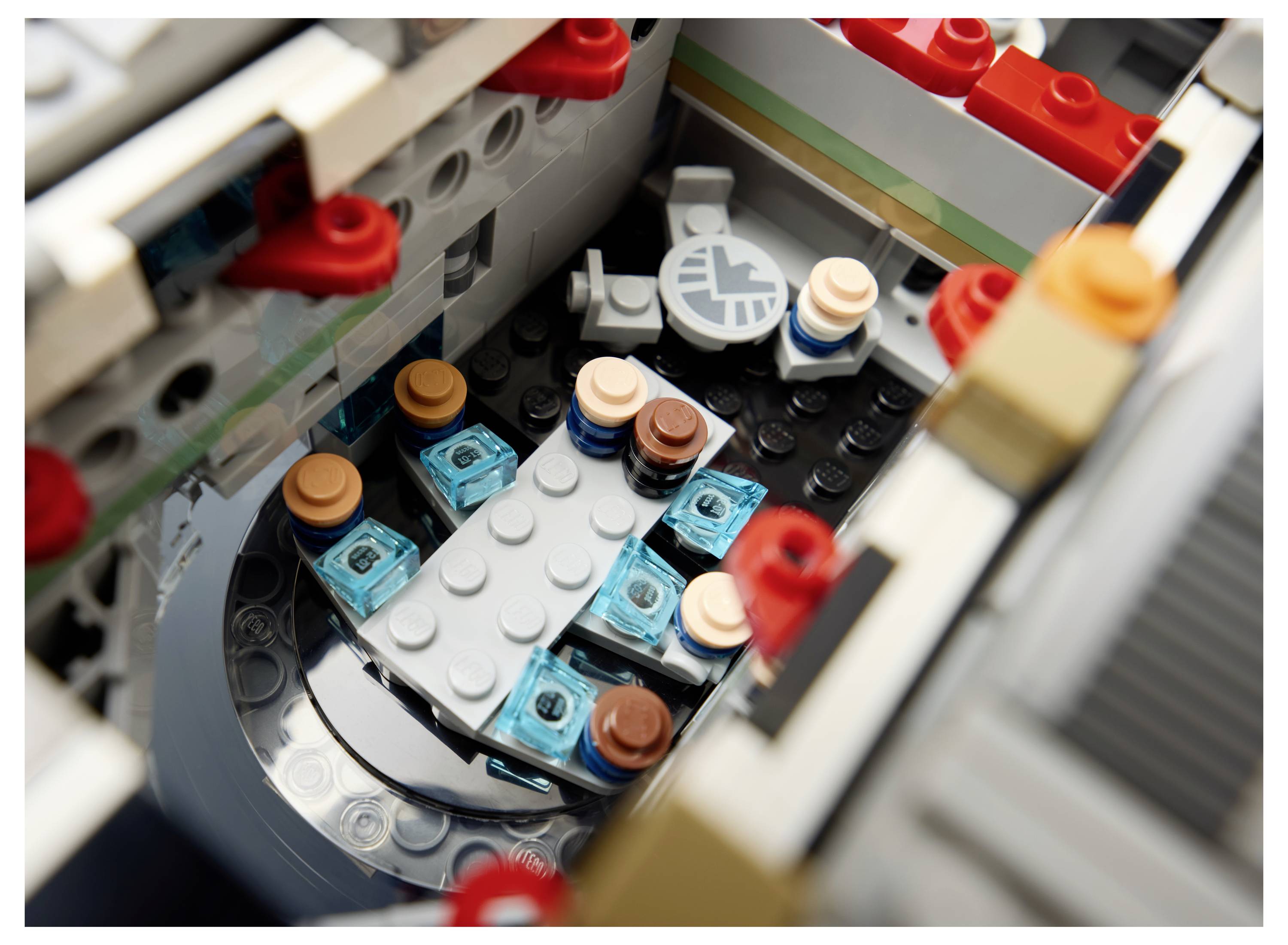 Detailní pohled na interiér stavby z LEGO s malým kulatým stolem a čtyřmi sedadly pro minifigurky v šedé místnosti.
