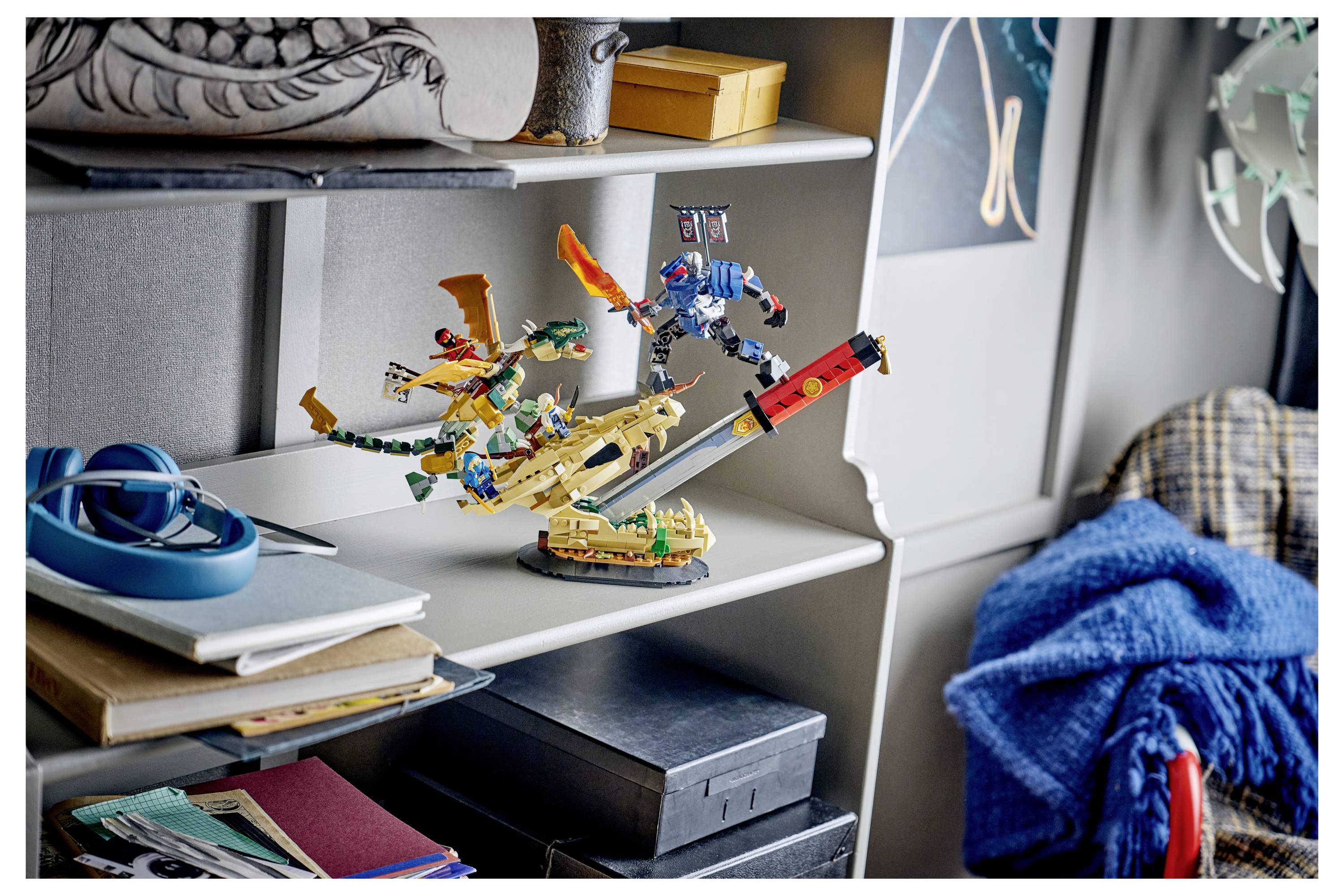 Dvě barevné figurky v LEGO stylu stylizované jako akční postavy v bojové pozici na béžovém vozidlu nebo tvorovi, vystavené na polici v pokoji podobném ložnici.