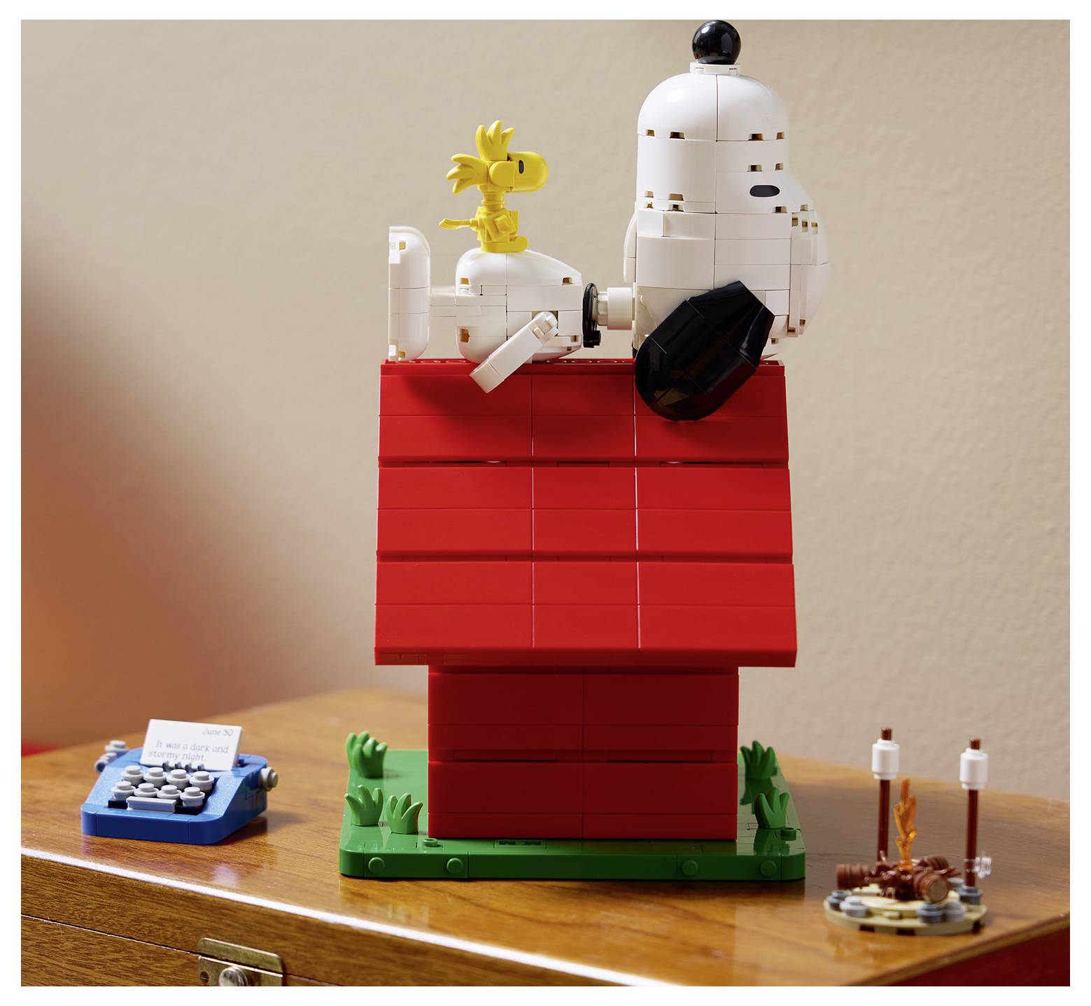 LEGO model Snoopyho na červené psí boudě s Woodstockem, vystavený na dřevěném stole.