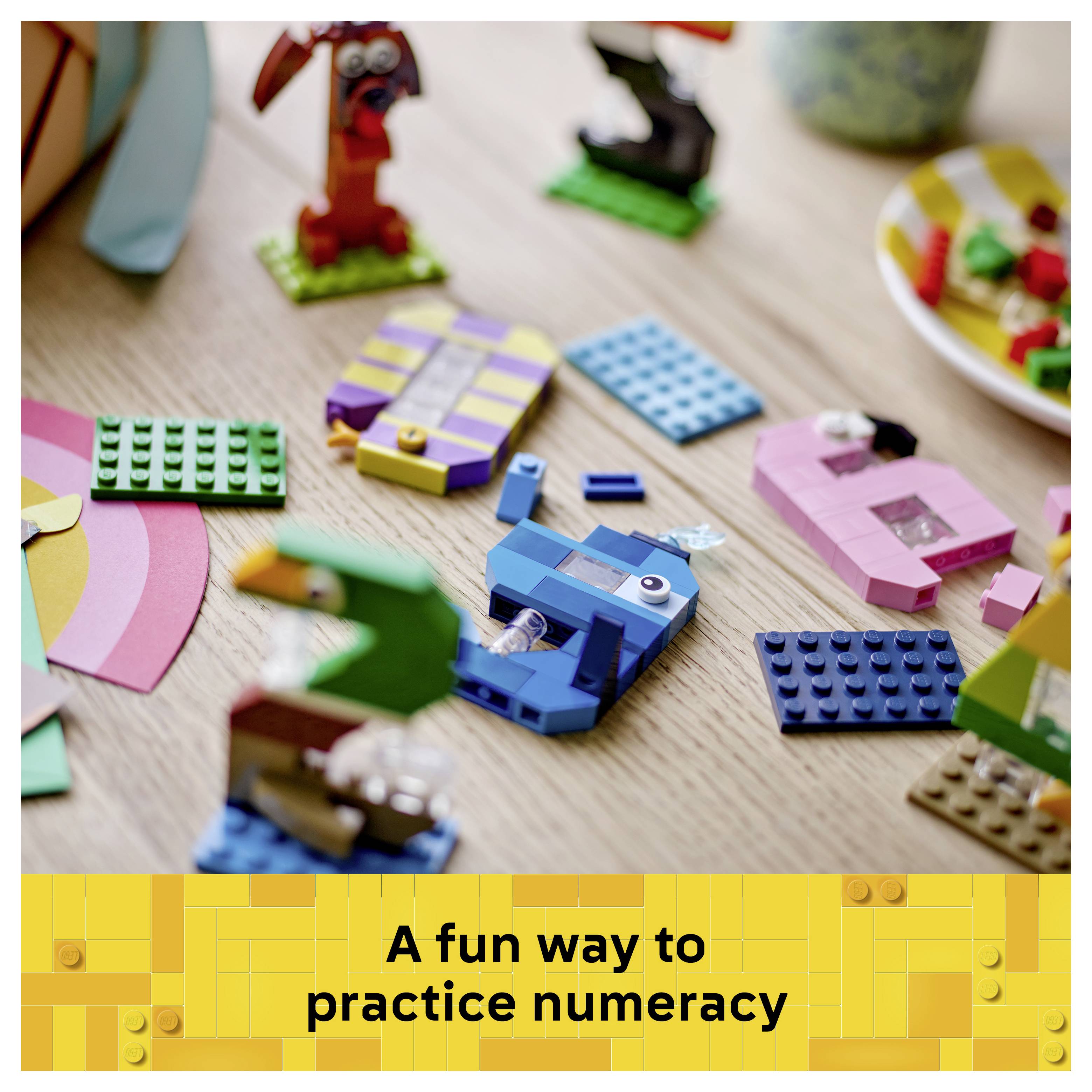 Barevné LEGO kostky rozptýlené na stole nad transparentem s textem „Zábavný způsob, jak procvičovat numerickou gramotnost".