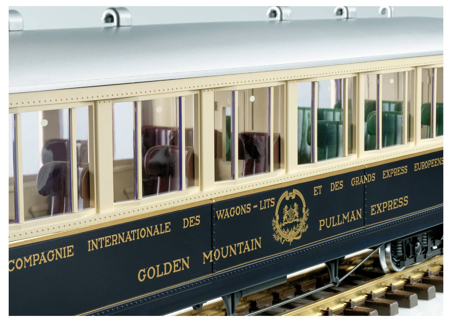 Modelový vlak s osobním vozem označeným "Compagnie Internationale des Wagons-Lits" a "Golden Mountain Pullman Express" na kolejích.