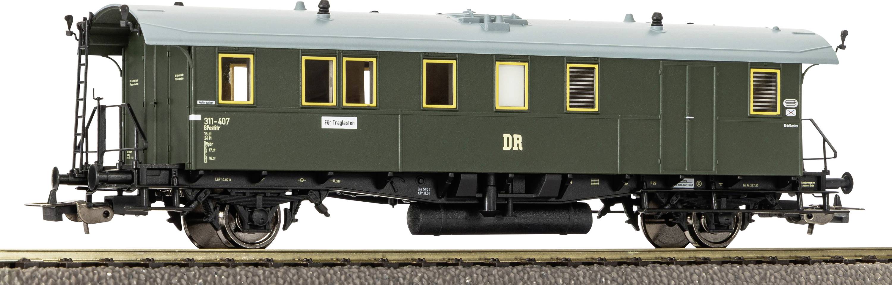 Tmavě zelený vintage železniční cestovní vůz se žlutě lemovanými okny a označením "DR", zobrazený ze strany na kolejích.