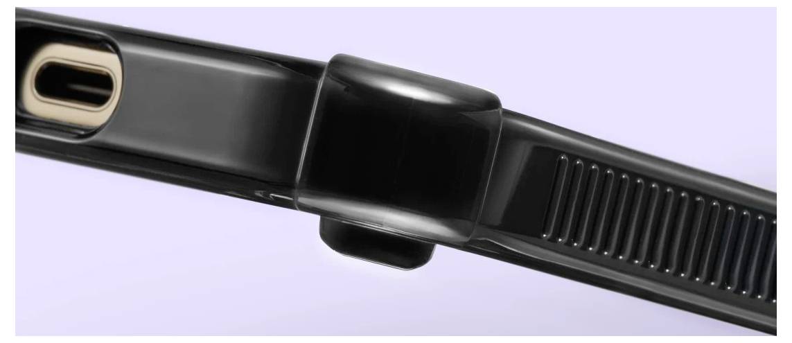 Detailní pohled na černý pás fitness trackeru nebo chytré hodinky s kovovou sponou na světle fialovém pozadí.