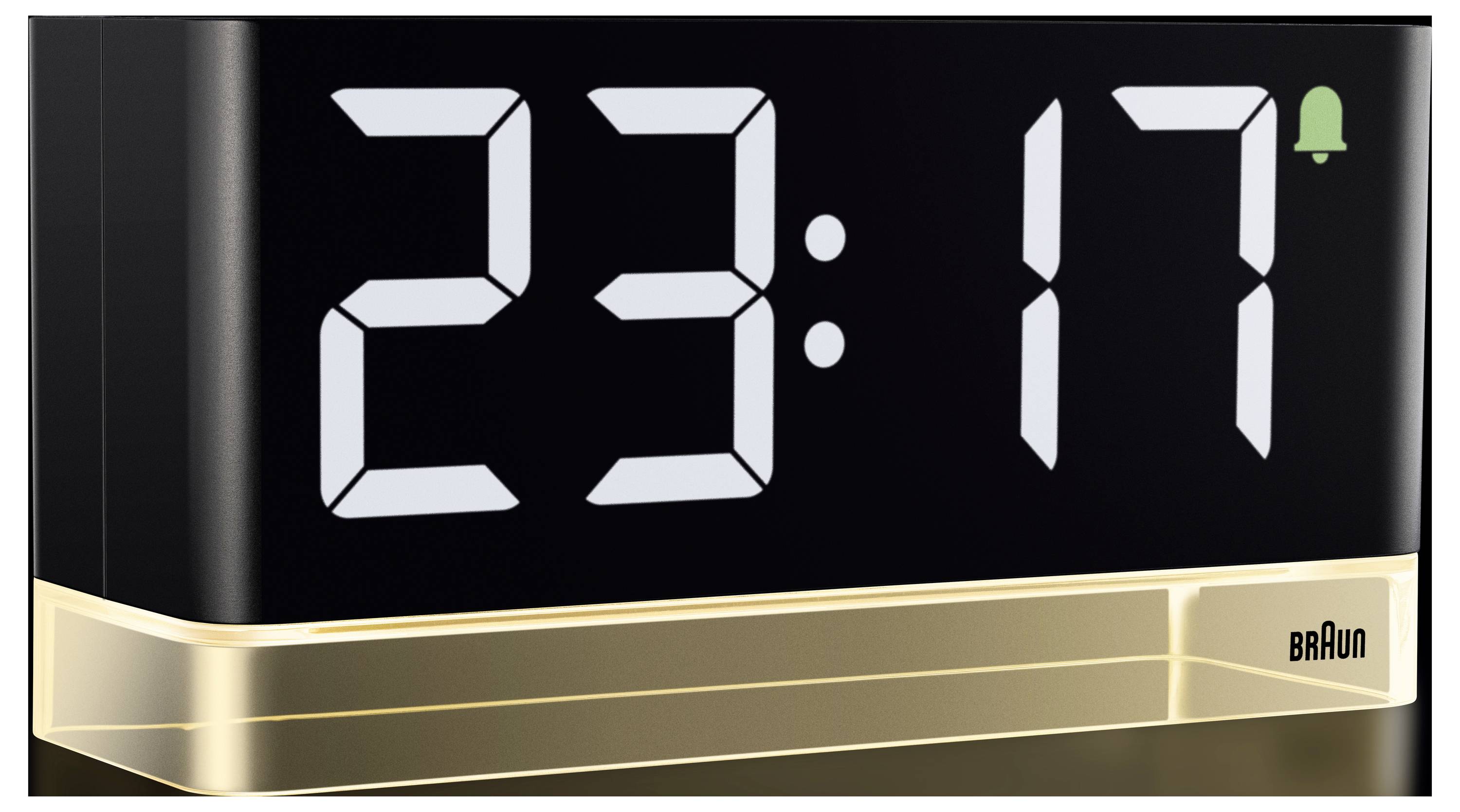 Digitální hodiny Braun zobrazující 23:17 s malou zelenou ikonou zvonku oznamující, že je nastaven budík.